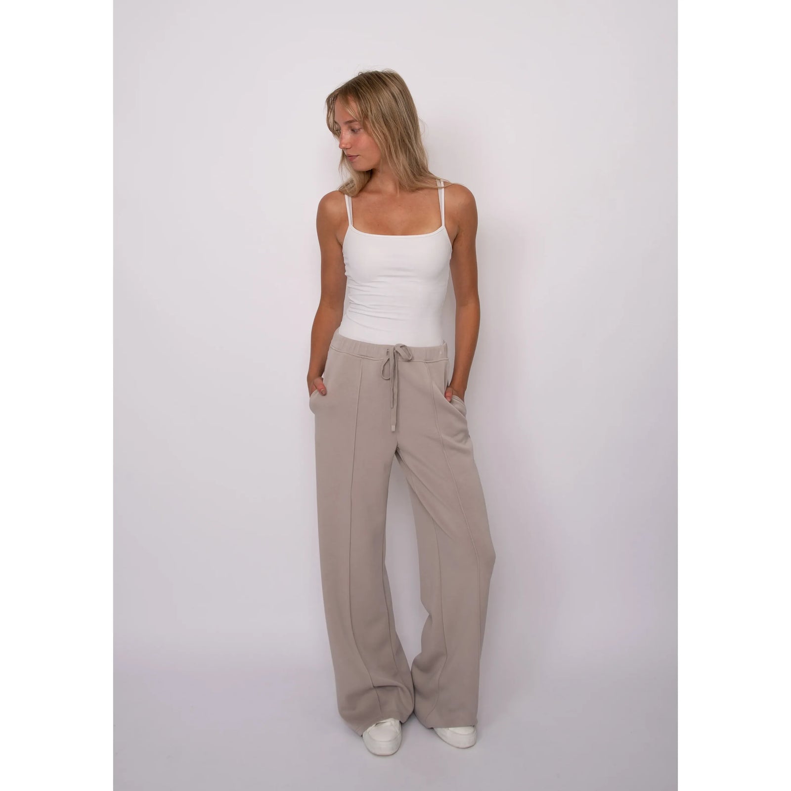 Model wearing beige soft knit pull-on drawstring pants with wide legs, featuring an adjustable waist and side pockets for comfort.