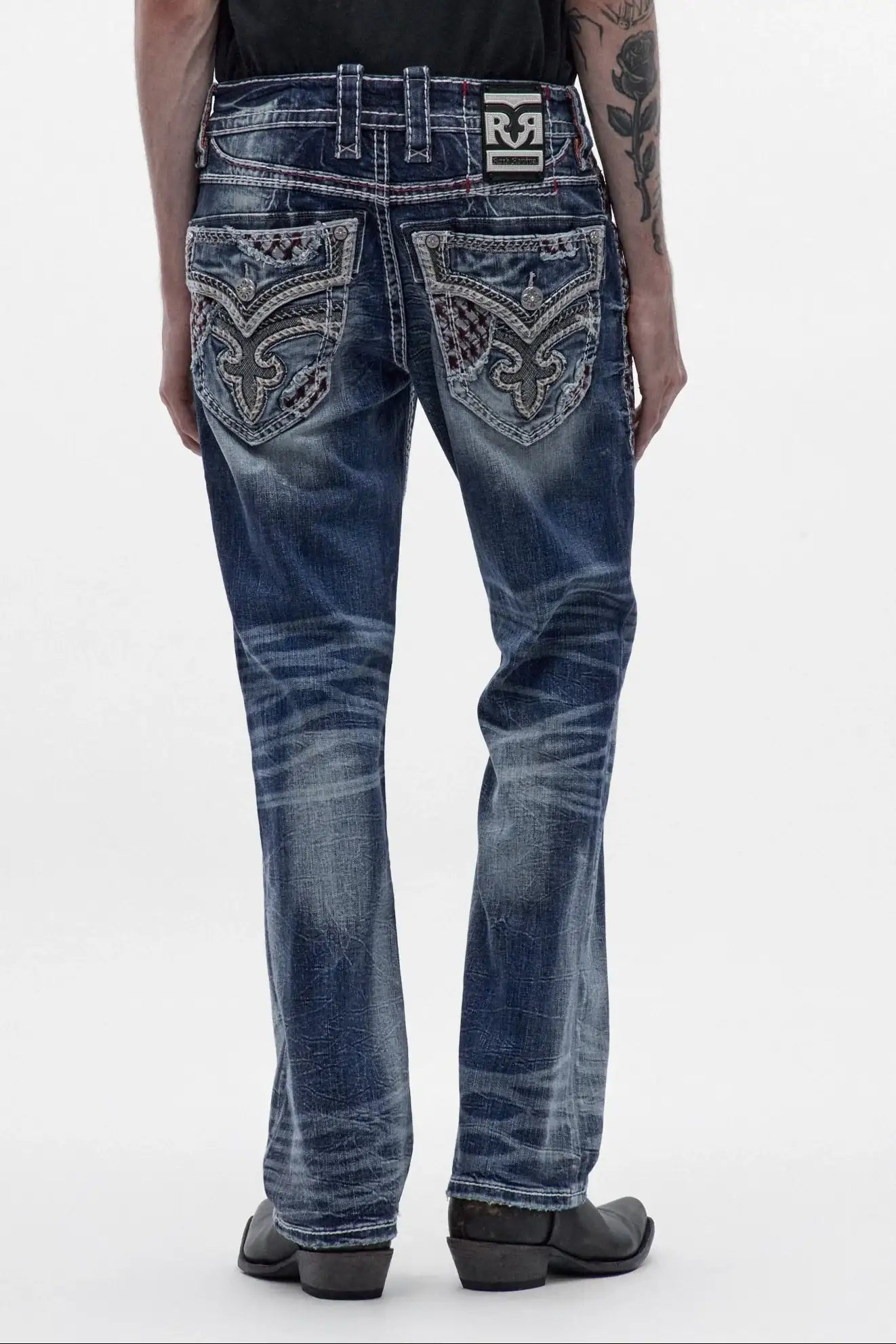 Men's medium blue bootcut jeans featuring ornate back pocket embroidery, whiskering, and a classic boot leg fit.