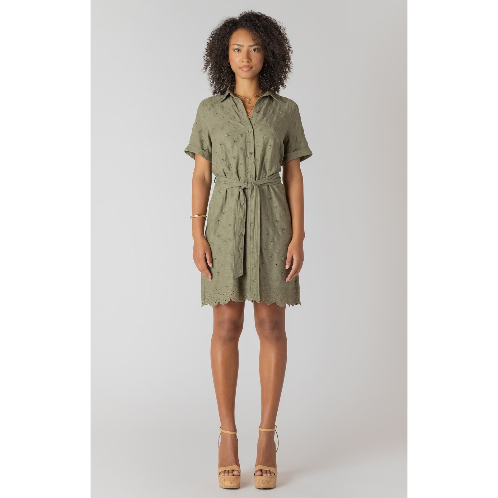 Room 34 linen belted mini shirt dress in sage with eyelet embroidery along hem, worn by a model.
