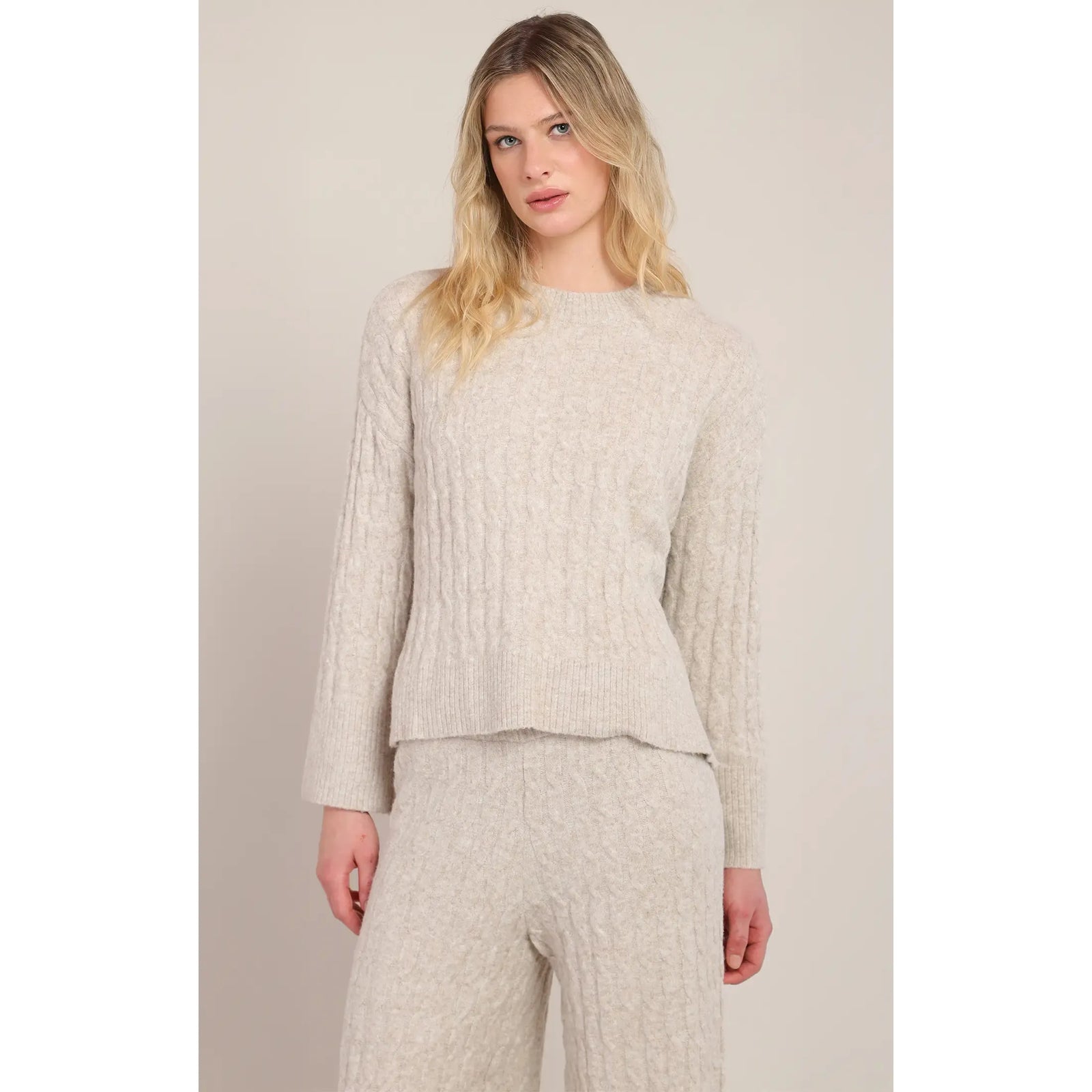 Beige cable knit sweater with crew neck and long sleeves, shown as part of a cozy wool-blend loungewear set.