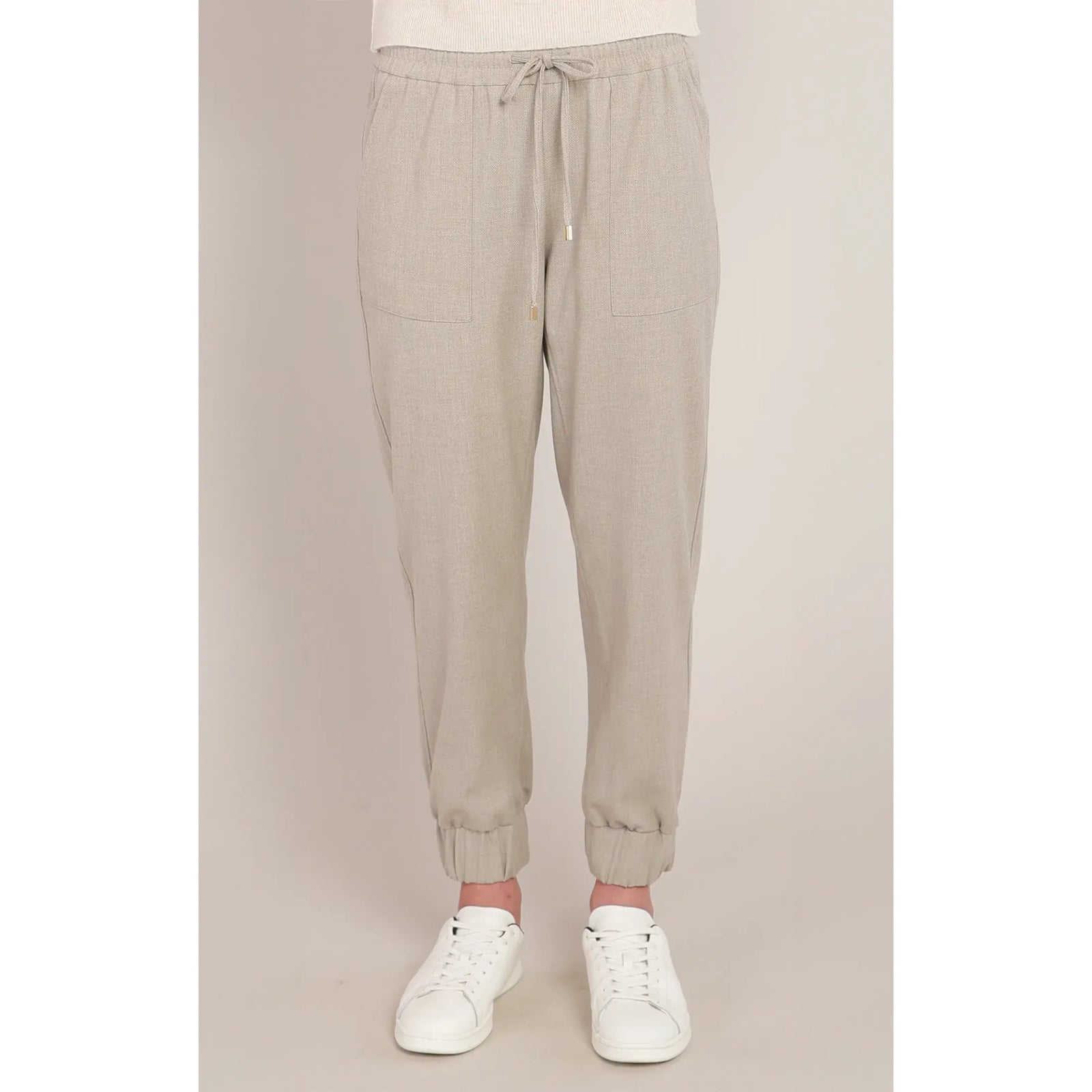Beige knit cuffed hem pants with drawstring waist, relaxed fit, and white sneakers for a chic casual look.
