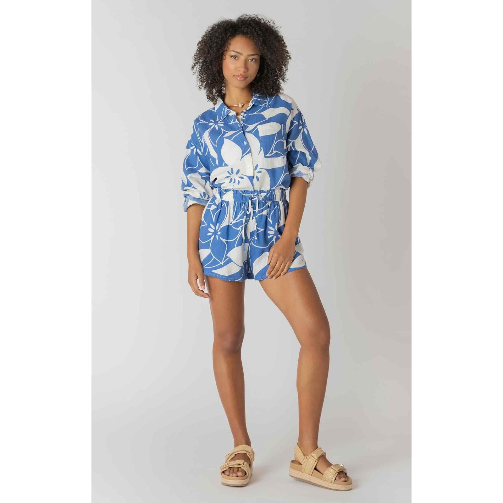 Model in azure floral Room 34 elastic waist shorts with a matching shirt, casual summer look.