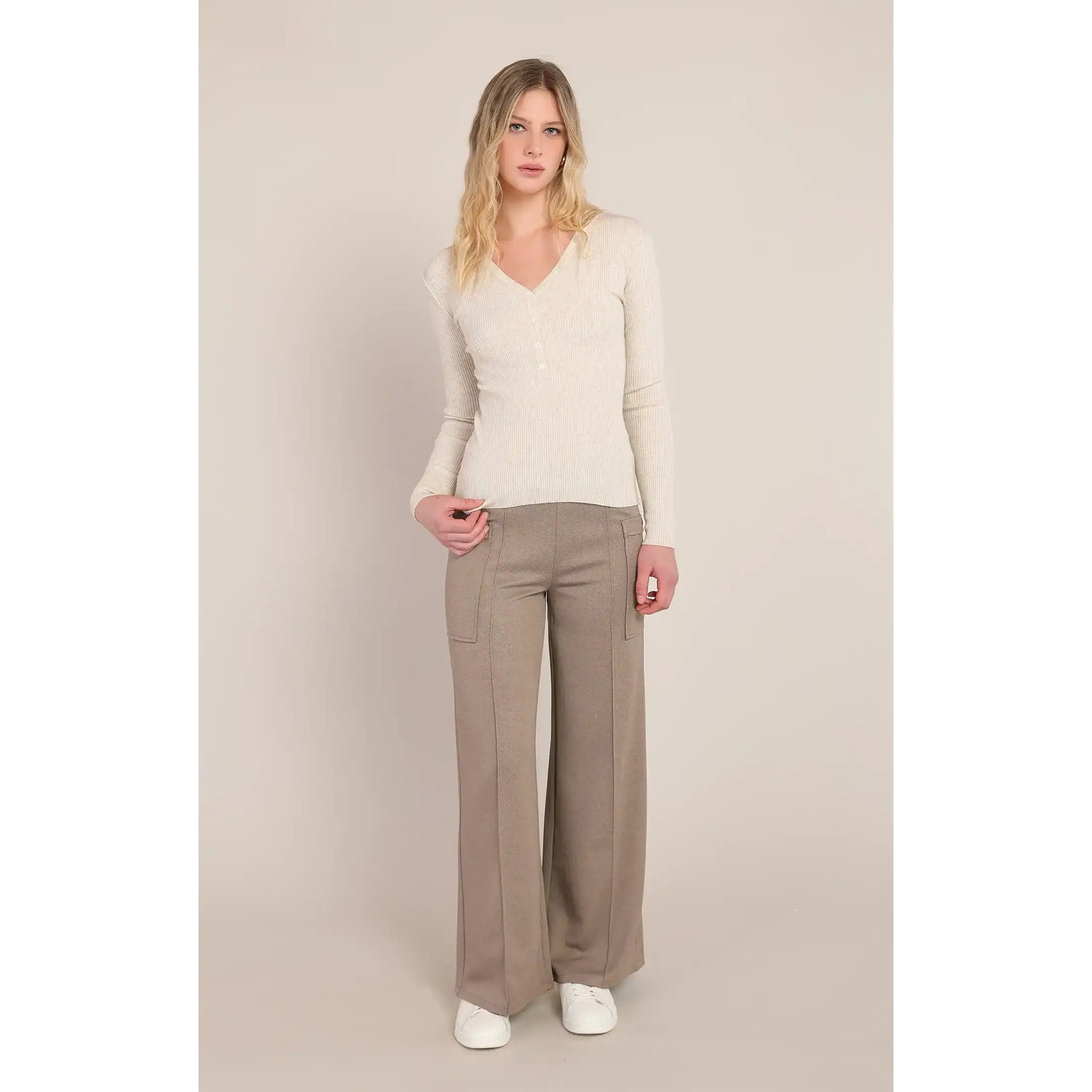Cream ribbed V-neck sweater with long sleeves, styled with wide-leg beige trousers and white sneakers for a cozy, versatile look.