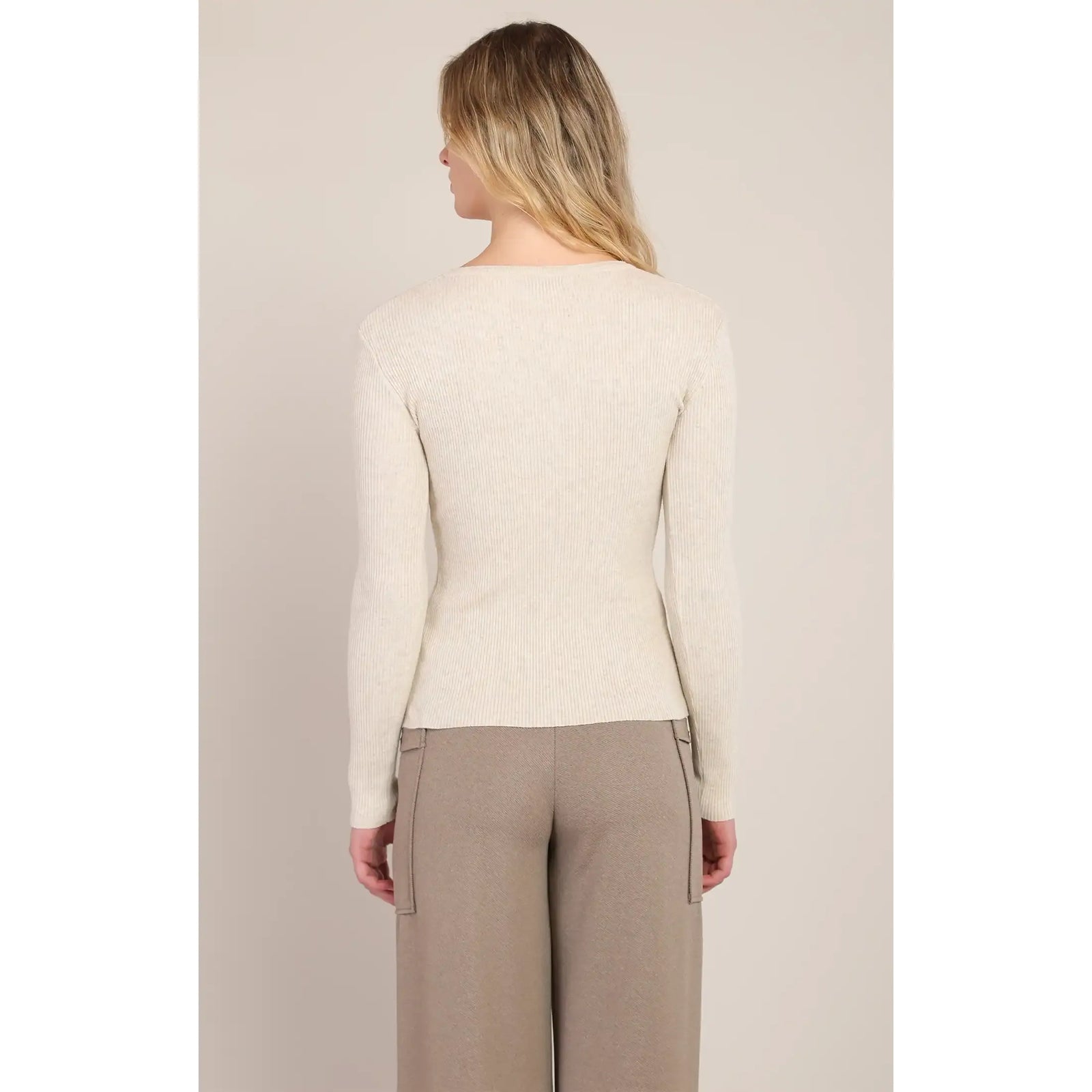 Back view of a cream ribbed V-neck sweater with long sleeves, paired with beige wide-leg trousers.