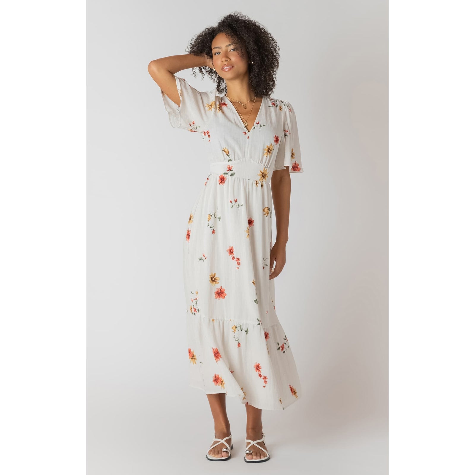Model wearing white floral Room 34 short-sleeve maxi dress with V-neck and flowing length.