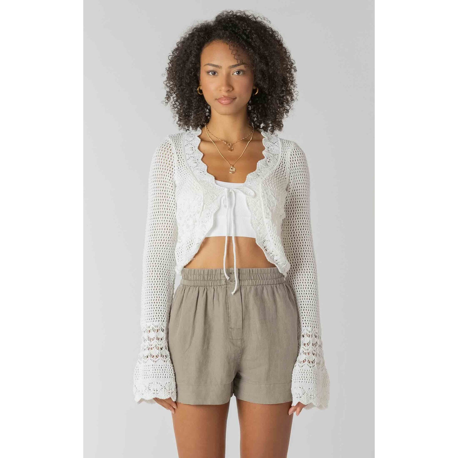 Room 34 Tie Front Crochet Cardigan with scalloped lace edges over white crop top and beige shorts.