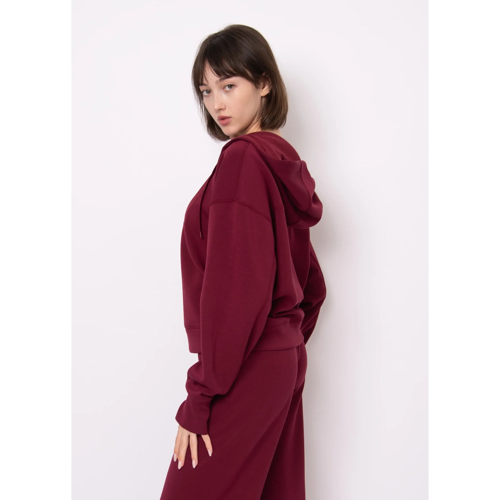 Model wearing Sallie Soft Knit Snap Front Hoodie in burgundy with hood.