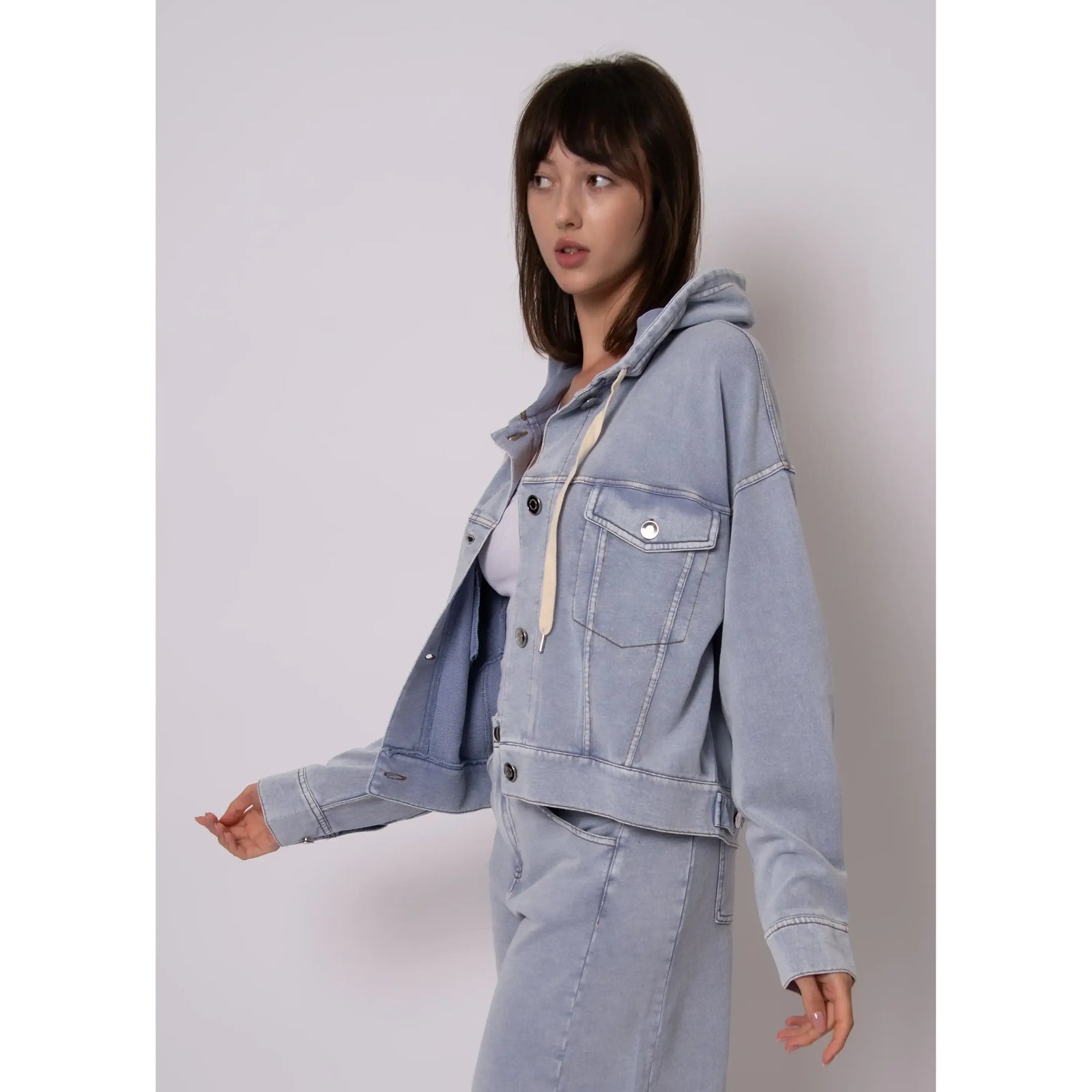 Model in Sarana French Terry Hooded Jacket: light denim with button front, chest pockets, beige hood drawstring.