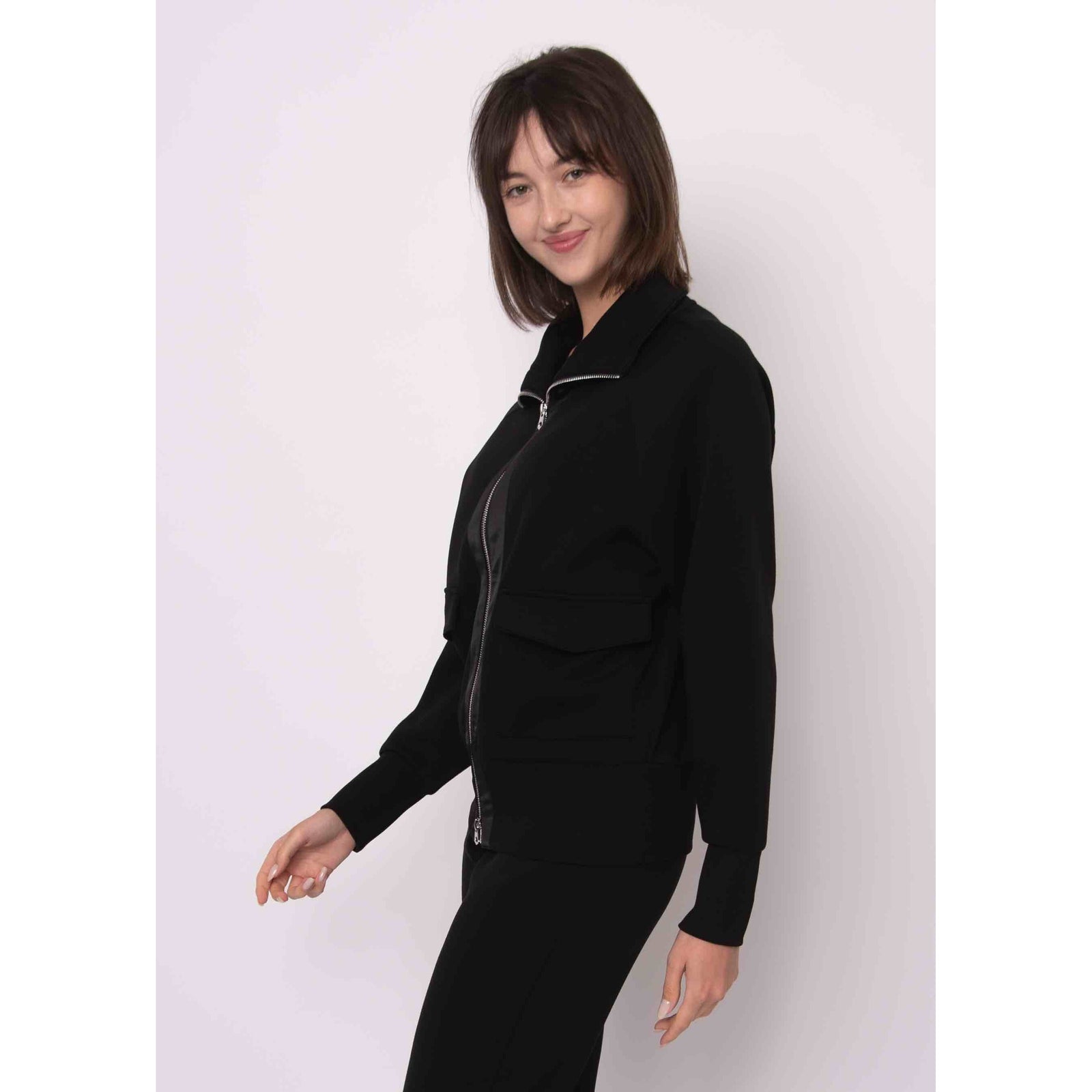 Model wearing a black Saruna Soft Knit Mock Zip Up jacket with a silver zipper.