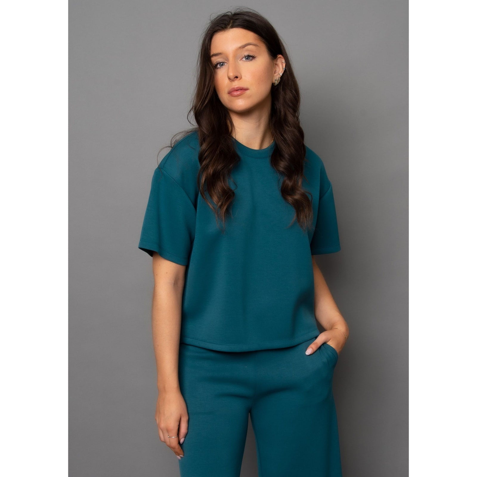 Stylish woman models the Scuba Tess Soft Knit Top in trekking green, ideal for casual outfits or denim pairing.