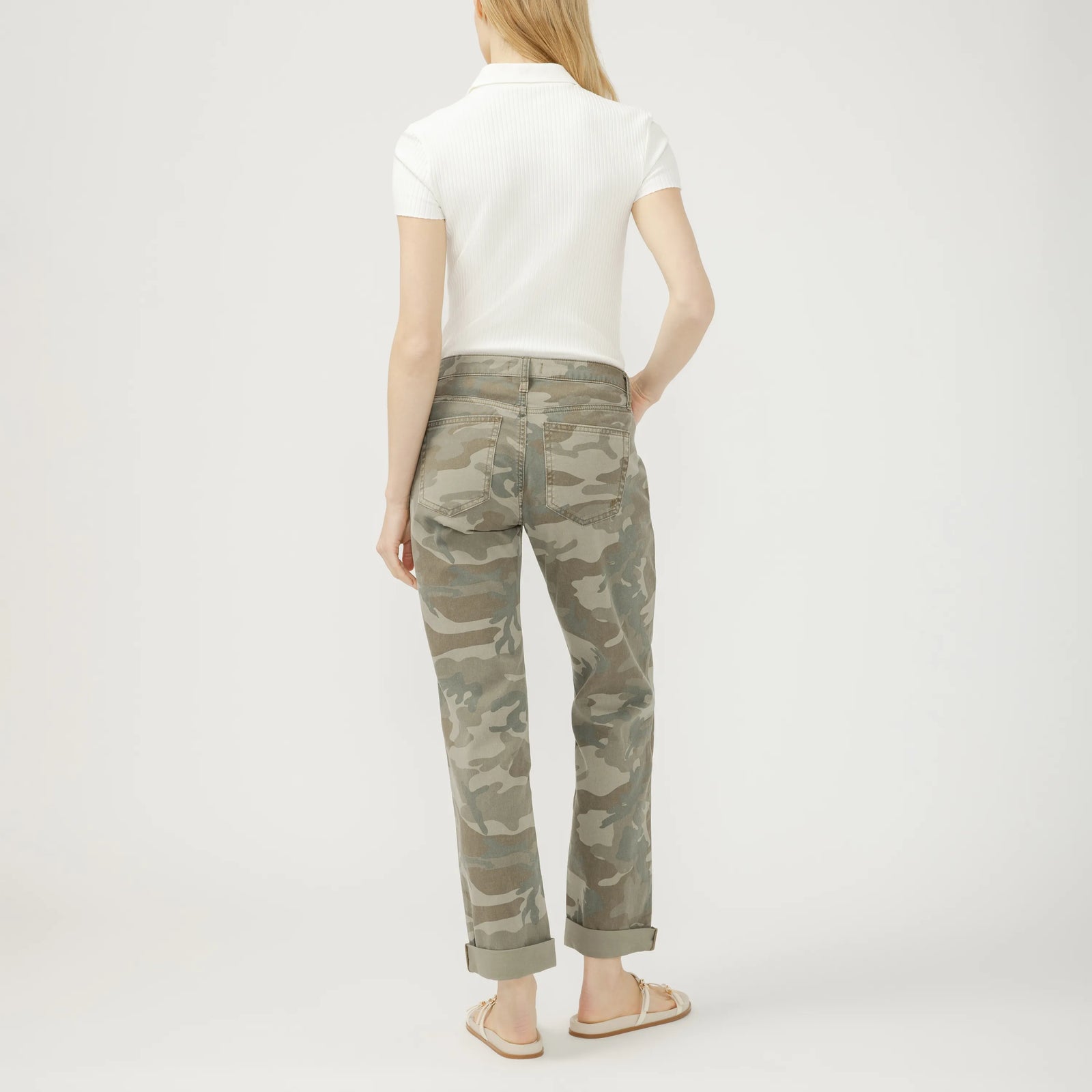 Back view of model wearing camouflage Chelsea Boyfriend jeans with rolled cuffs.