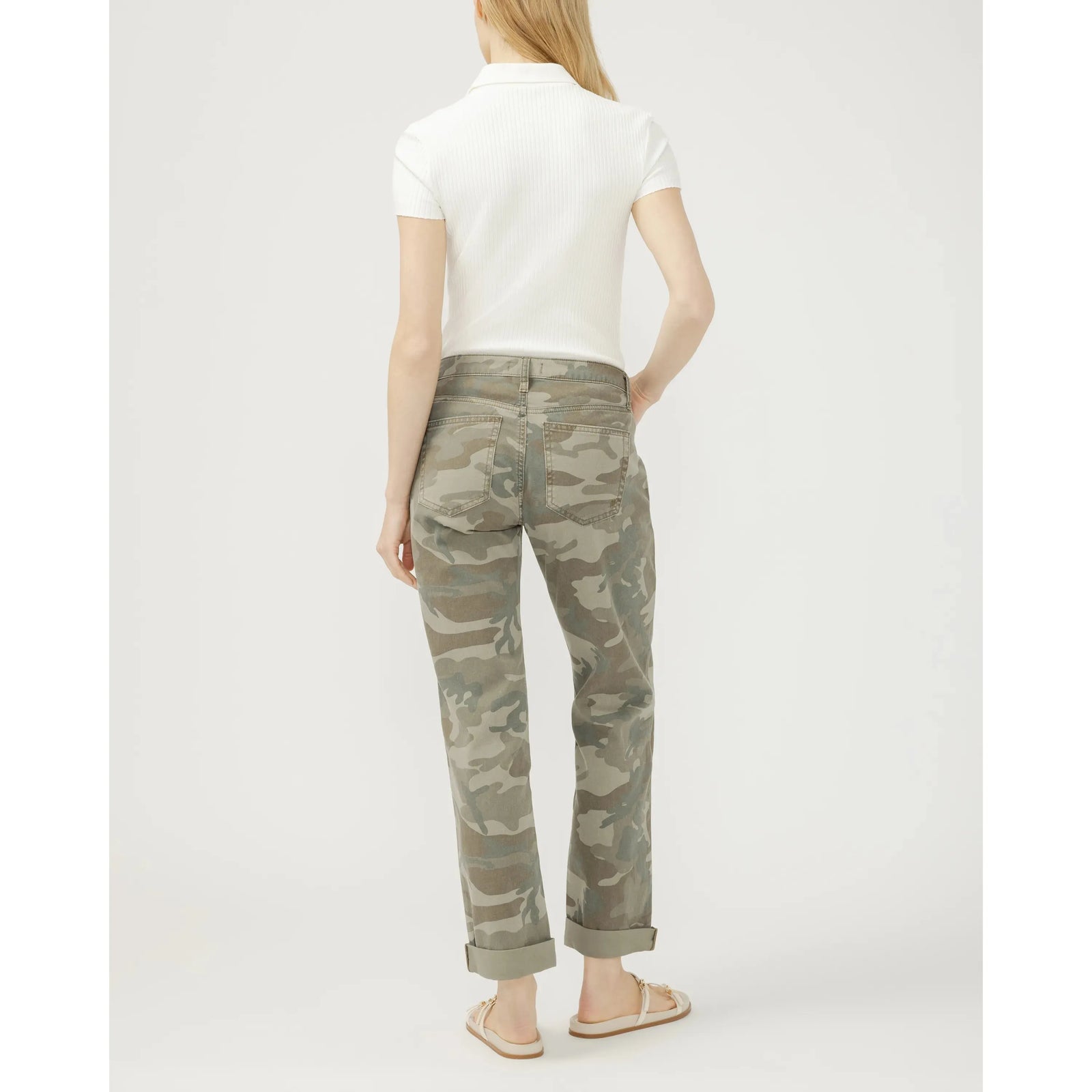 Back view of model wearing camouflage Chelsea Boyfriend jeans with rolled cuffs.