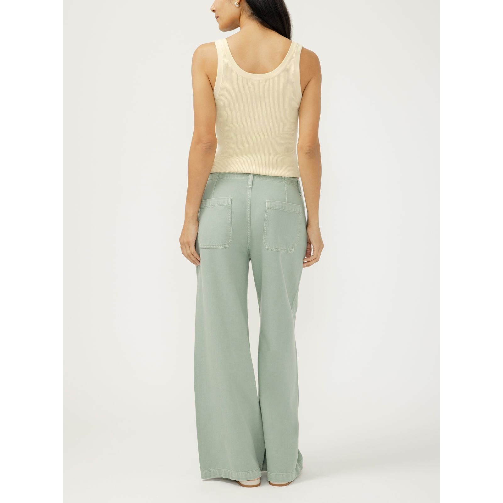 Sage-green wide-leg drawstring beach pants with back pockets worn by a model in a cream ribbed tank.