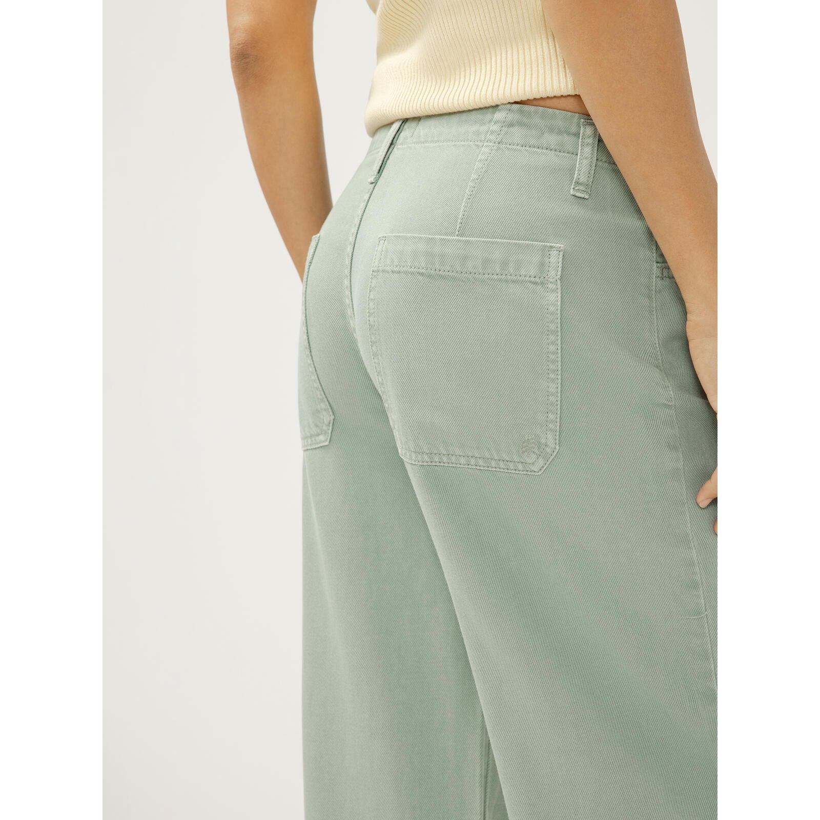 Light sage-green wide-leg denim pants with back pockets and relaxed fit.