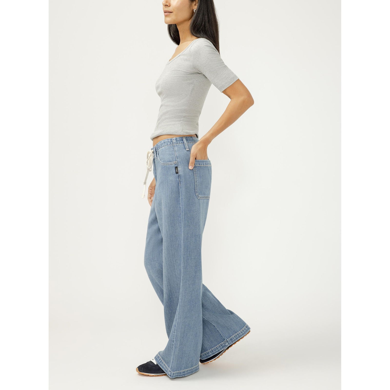 Model wearing silver wide-leg drawstring beach pants with a relaxed fit in medium indigo wash