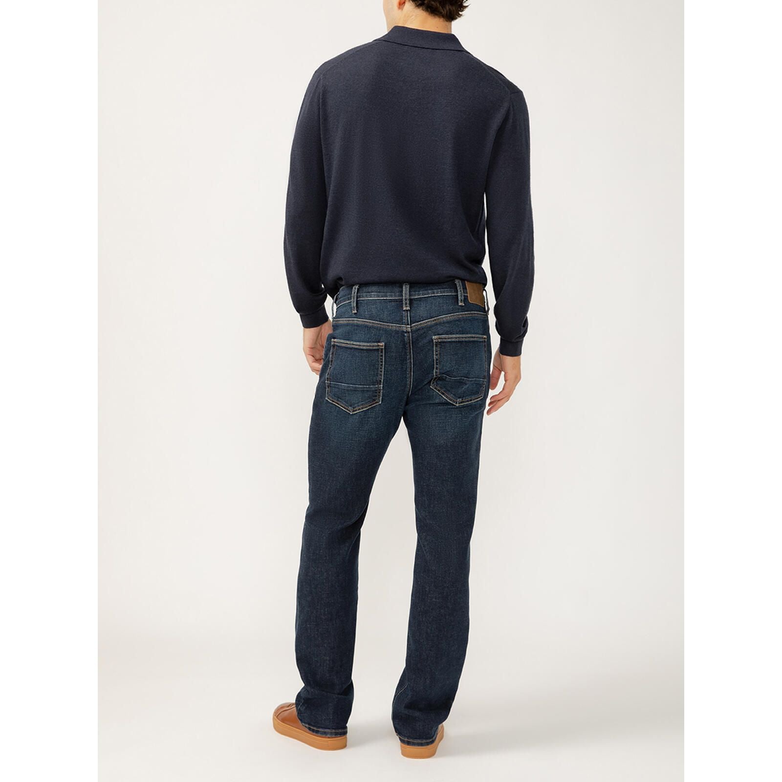 Back view of male model in Silver Jace Slim Bootcut Luxe in Swing jeans, navy top, brown belt.