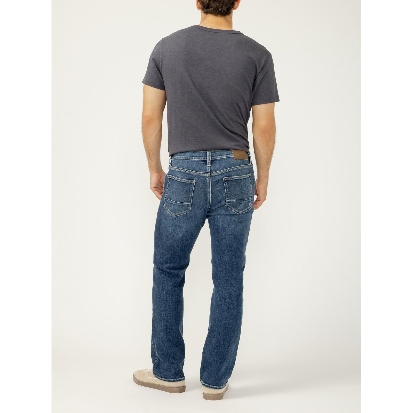 Back view of a man wearing Silver Jace Slim Bootcut jeans in Tate with a leather patch on the waistband.