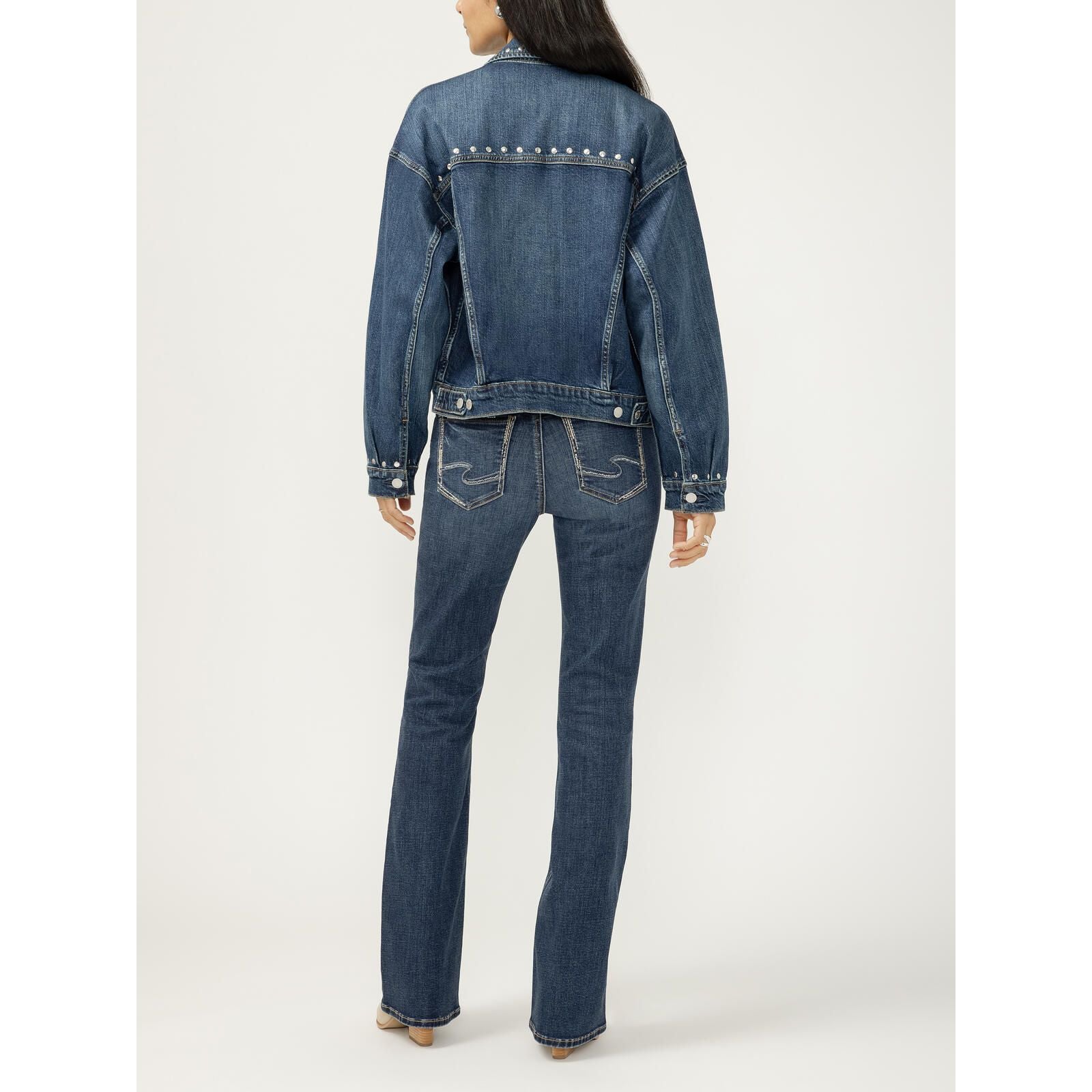 Back view of a blue denim jacket with silver studs along the upper back yoke.
