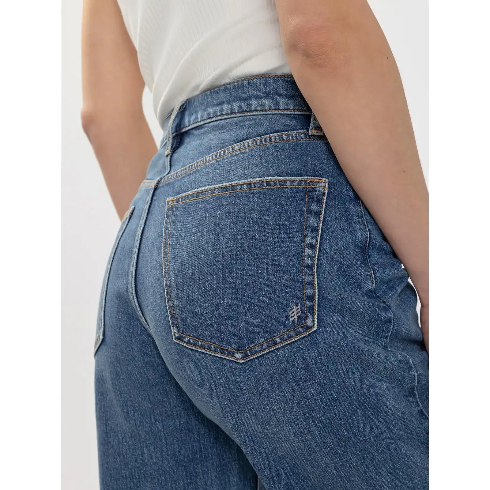 Back view of silver wide leg jeans featuring a curved waistline, gold stitching, and an embroidered logo on the back pocket.