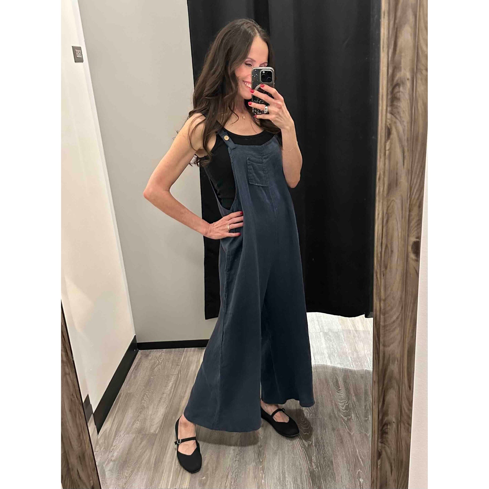 Navy Sorella Linen Jumpsuit with Pockets, oversized wide-leg, adjustable straps, model in fitting room.