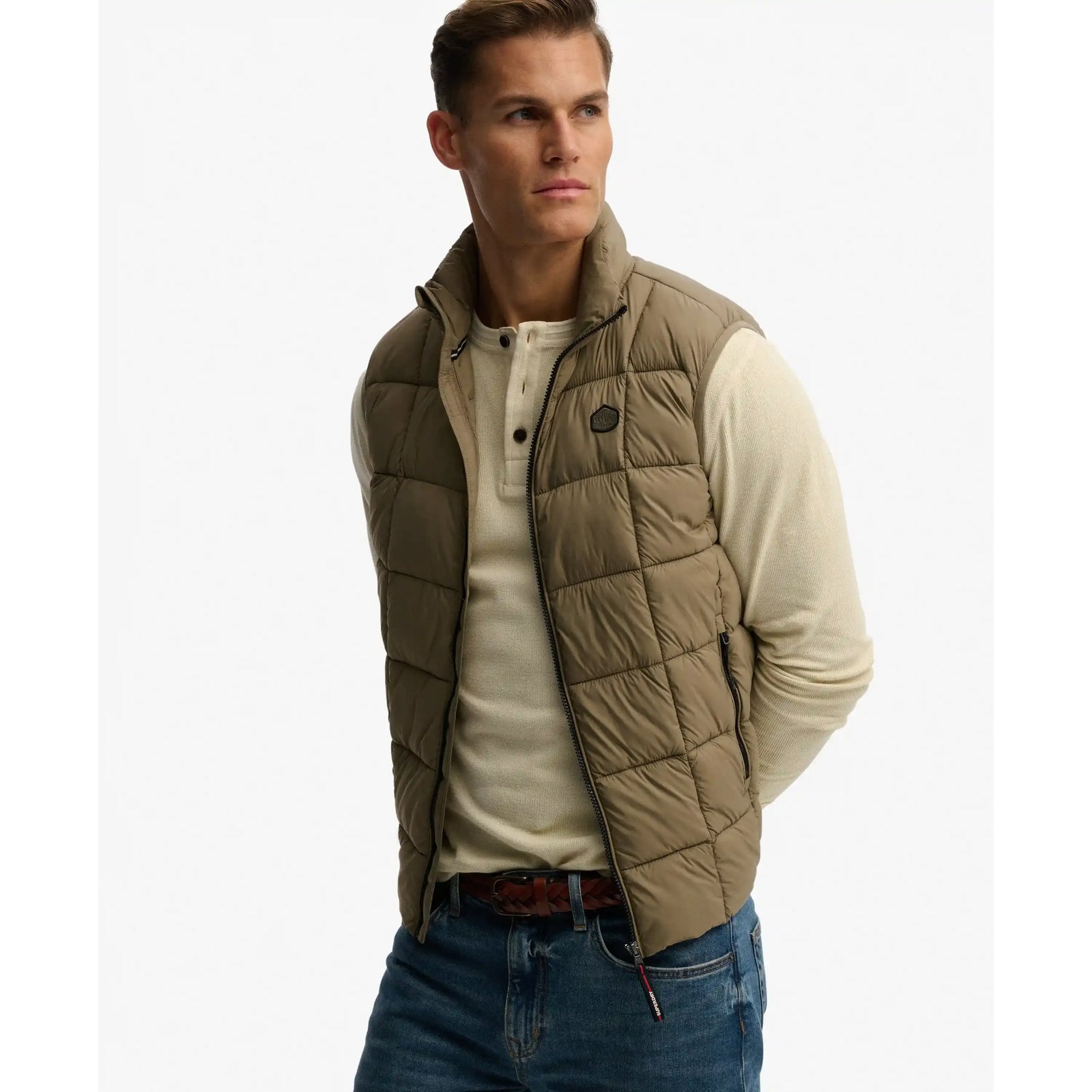 Model wearing Superdry Box Quilt Fuji Lite Gilet, tan quilted vest with zip front.