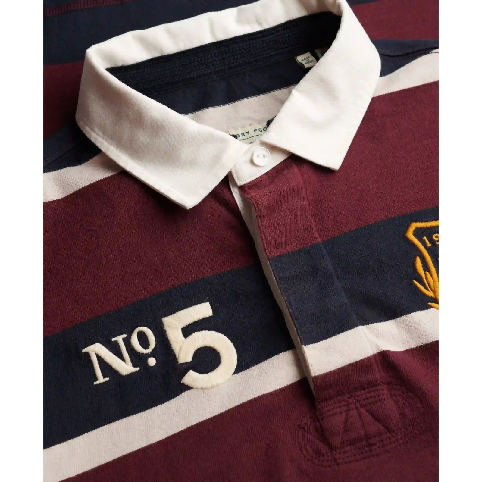 Superdry rugby shirt with maroon, navy, and white stripes, white collar, No. 5 embroidery and crest badge.