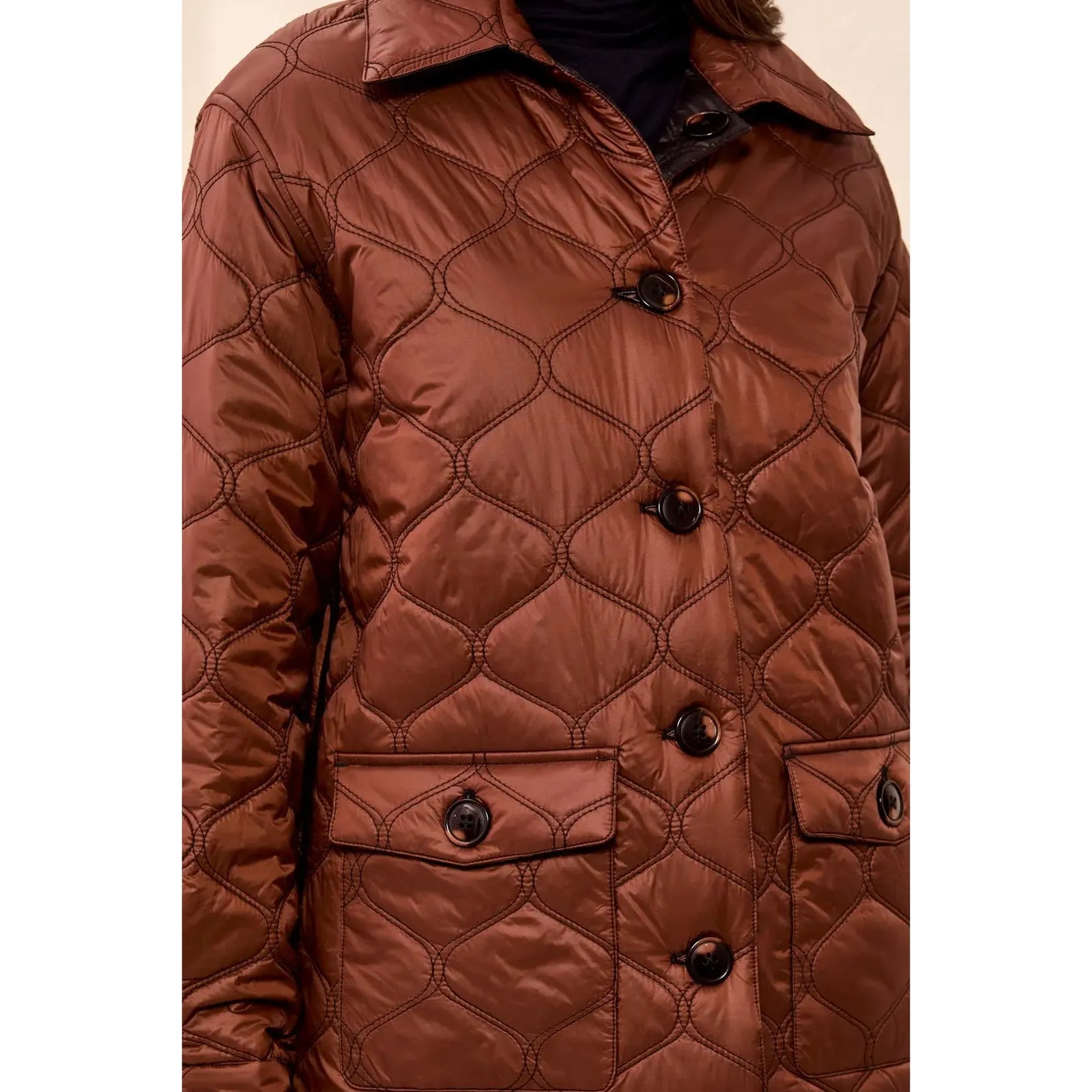 Copper-toned quilted jacket with geometric stitching, button closures, and flap pockets; reversible to black.