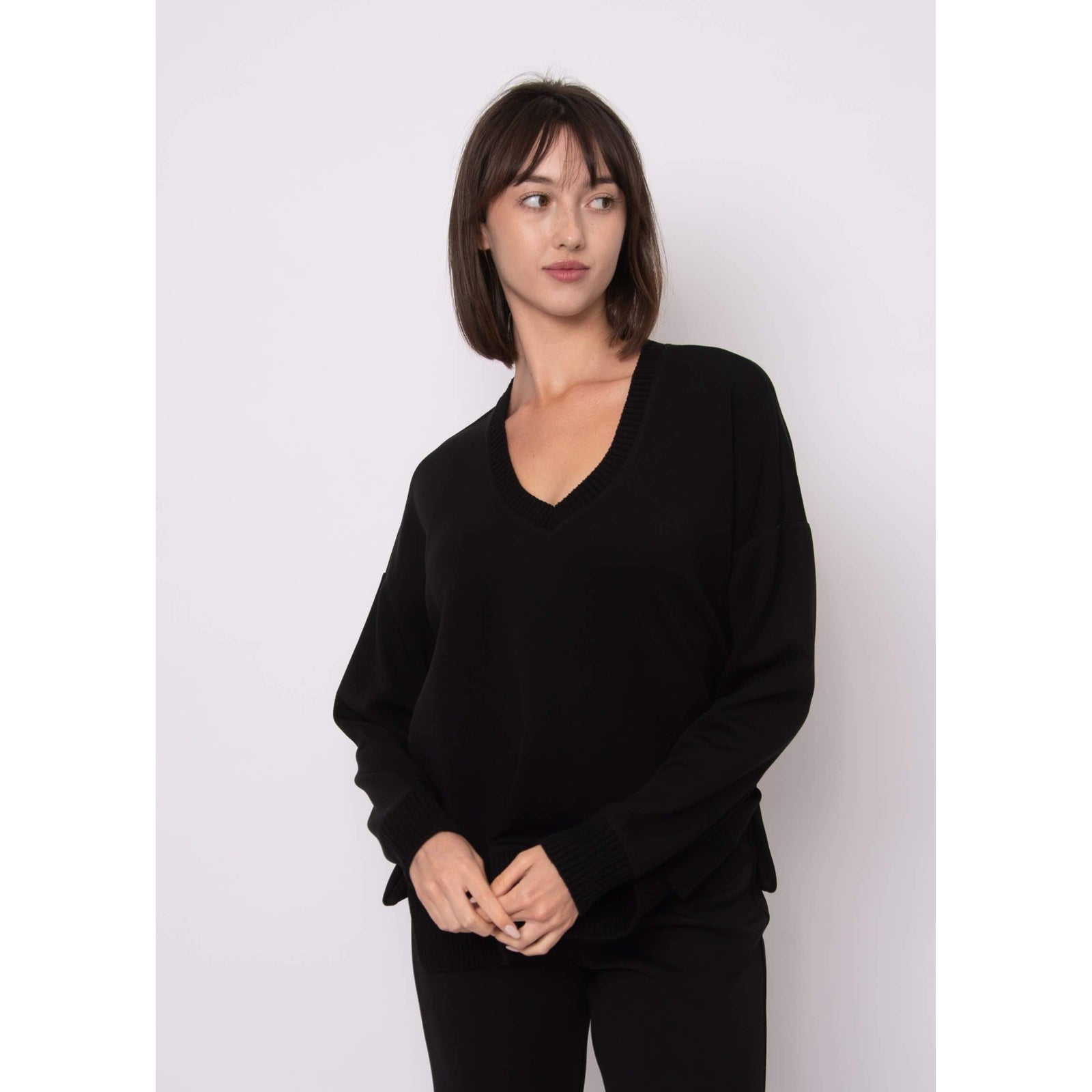Model wearing Vixie Soft Knit Vneck Sweater in black with a ribbed Vneck, relaxed fit.