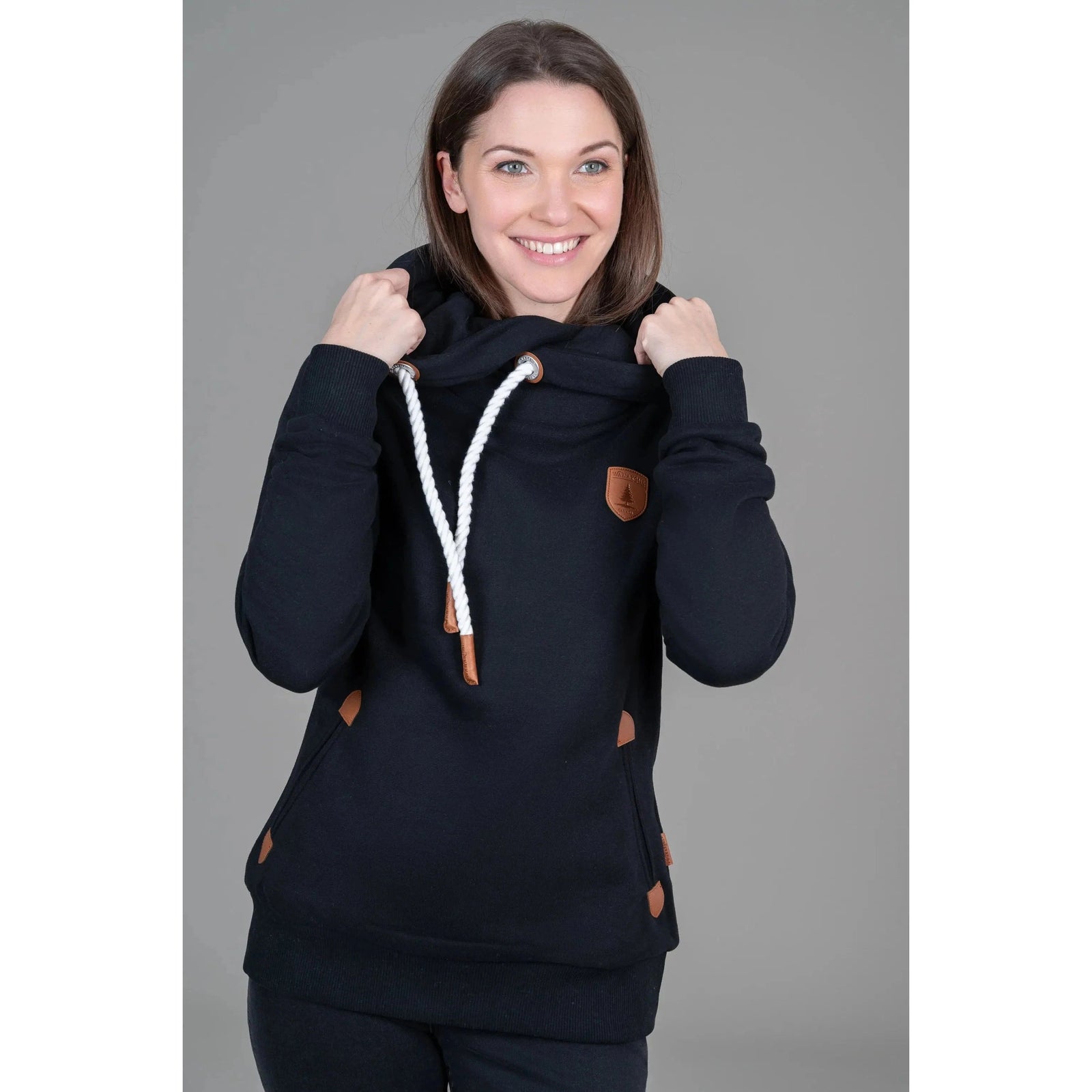 Wanakome Artemis Hoodie on a model; cozy black pullover with white drawstrings and leather accents.