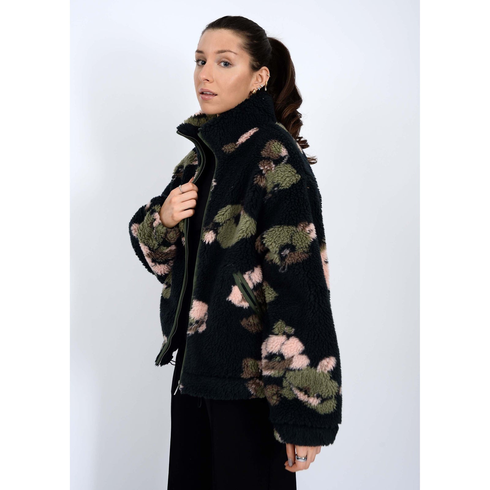 Whistler Sherpa Jacket worn by model, black teddy fabric with green-pink camo, collar, zip closure, drawstring hem