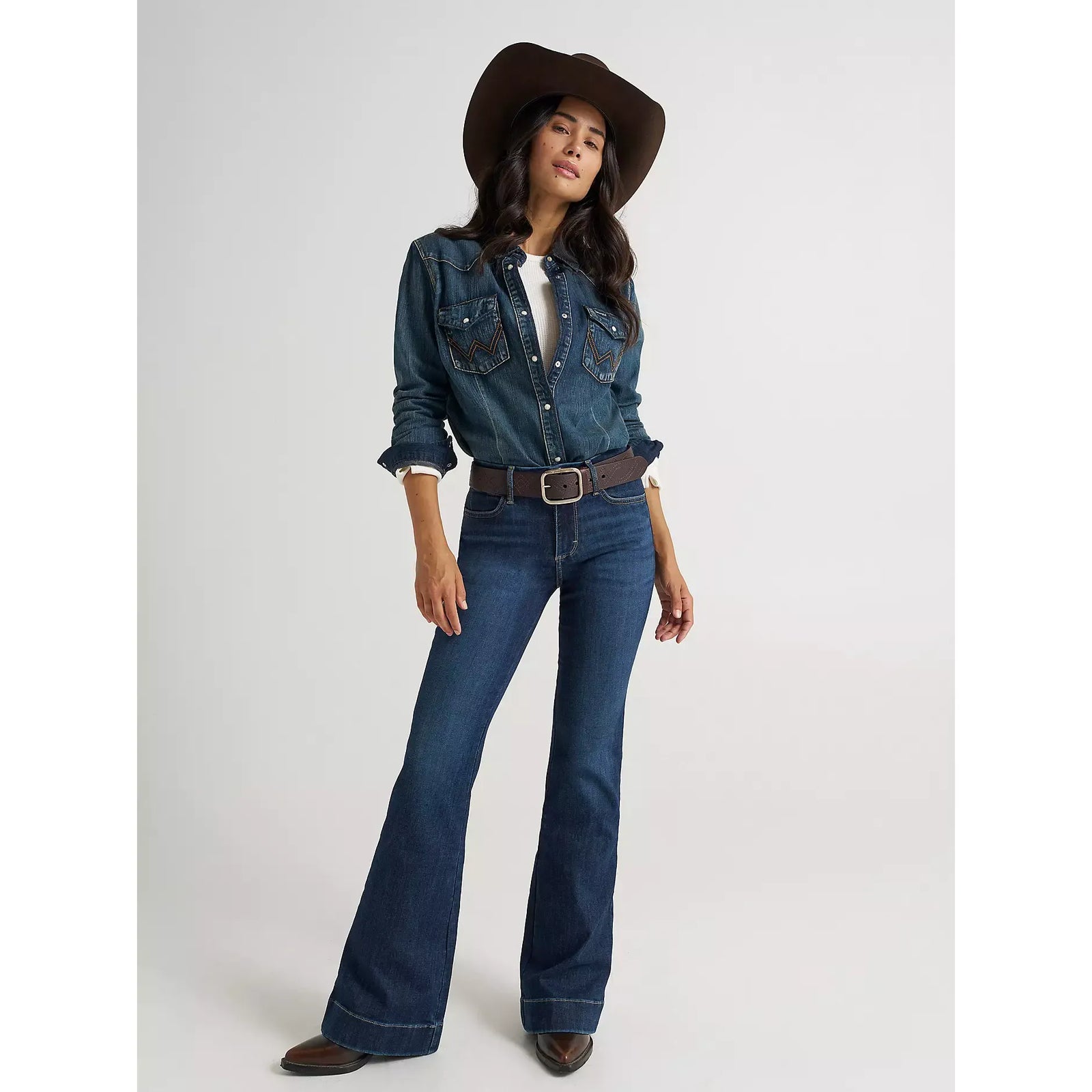 Model wearing Wrangler Bespoke Alexandra high-rise denim trousers with a flared hem and belt.