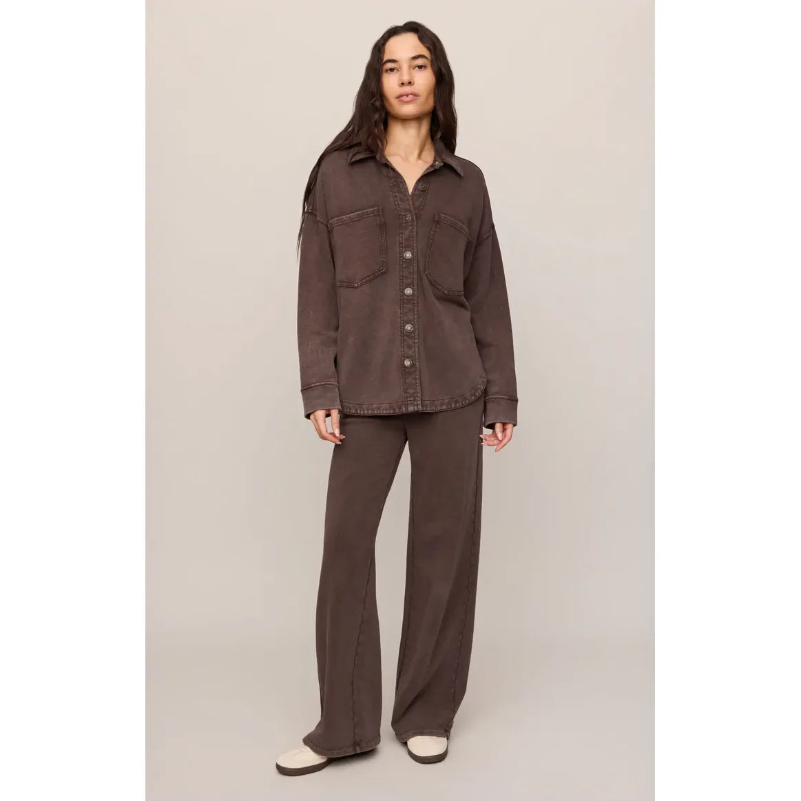 Model wears a dark brown knit jacket with front pockets and matching wide-leg pants, showcasing a timeless, vintage-inspired silhouette.