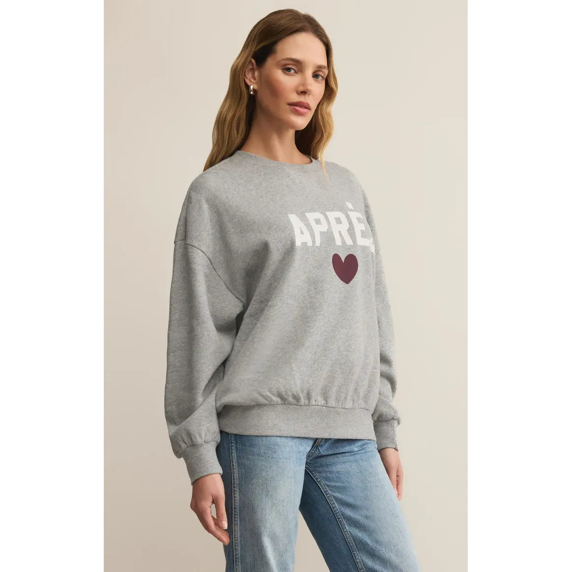 Gray oversized Z Supply Après Sunday Sweatshirt with white 'Après' graphic and maroon heart on model