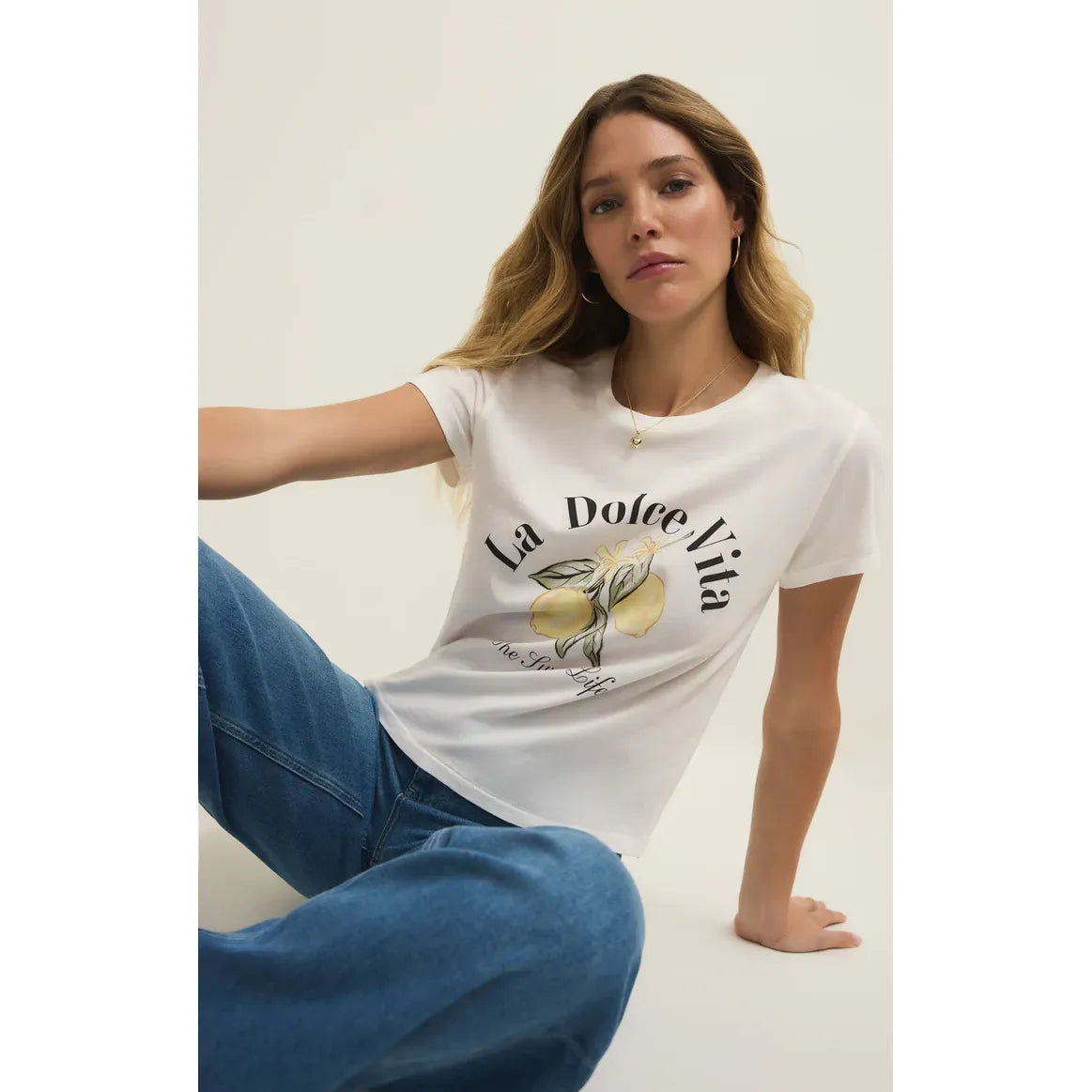 Model wearing a white Z Supply Dolce Tourist Tee with lemon graphic and retro typography, relaxed fit for warm weather.