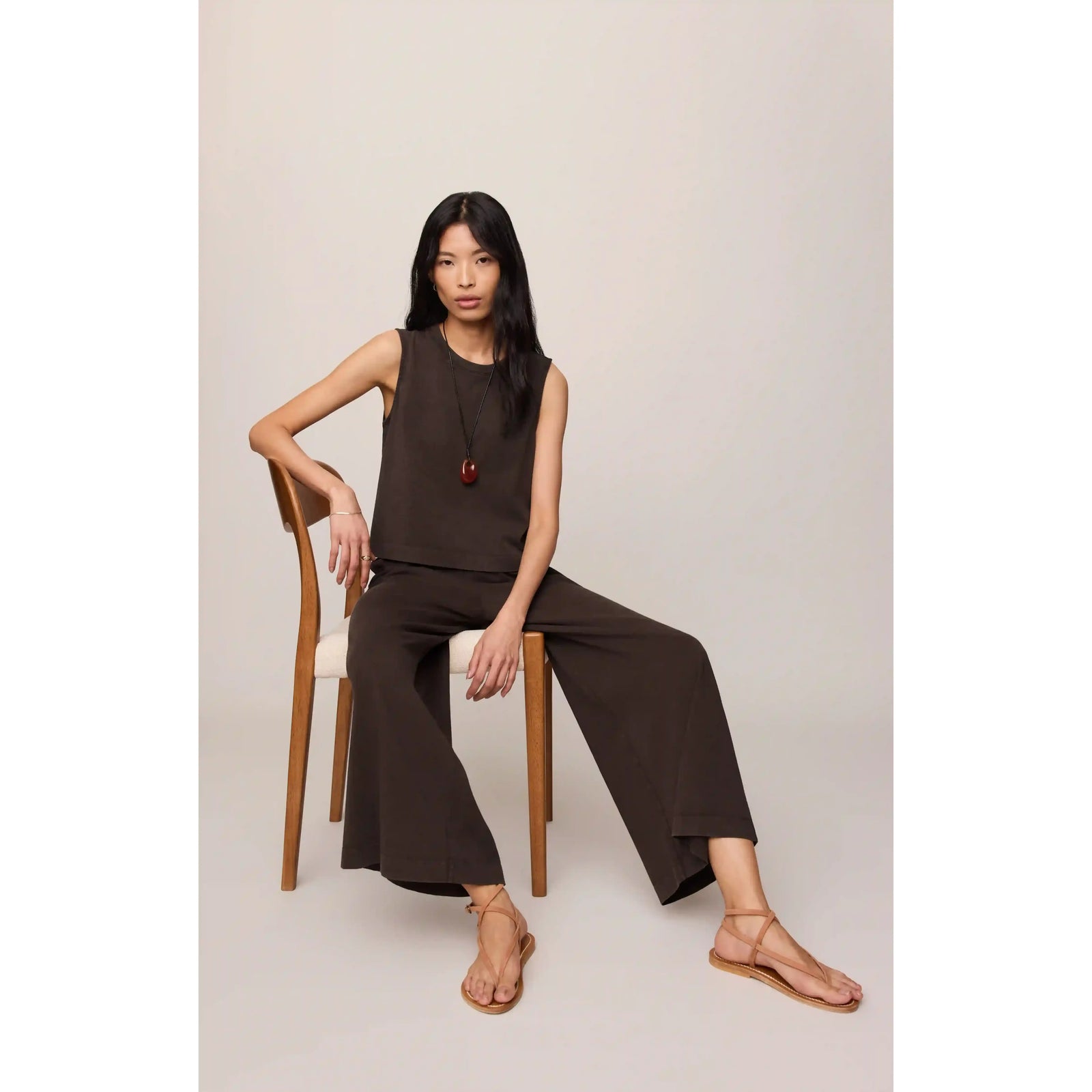Z Supply Scout Jersey Crop Flare Pant worn by a model in brown sleeveless top; seated on chair.