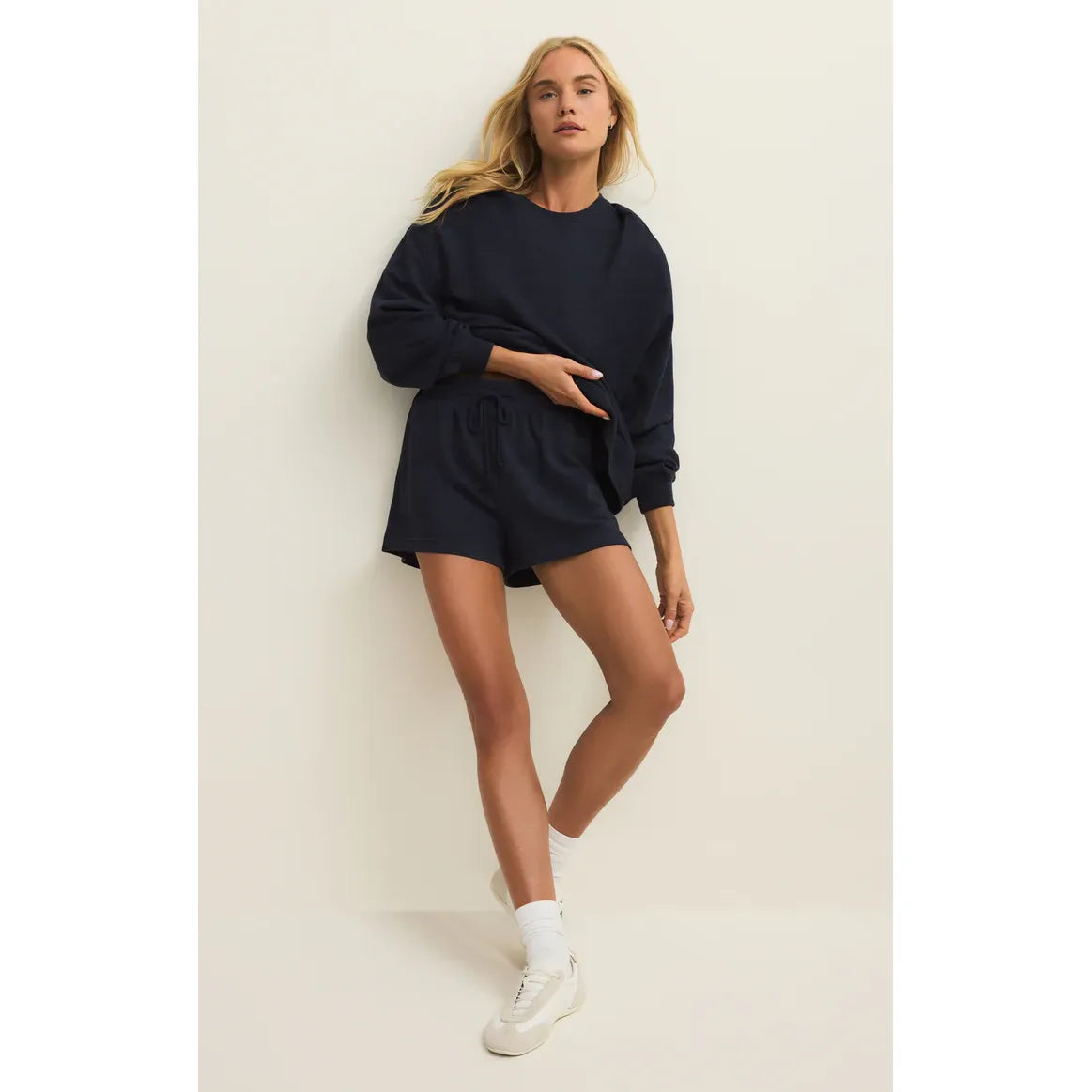 Model in navy Z Supply Modern Weekender Sweatshirt with matching shorts, relaxed-fit loungewear.