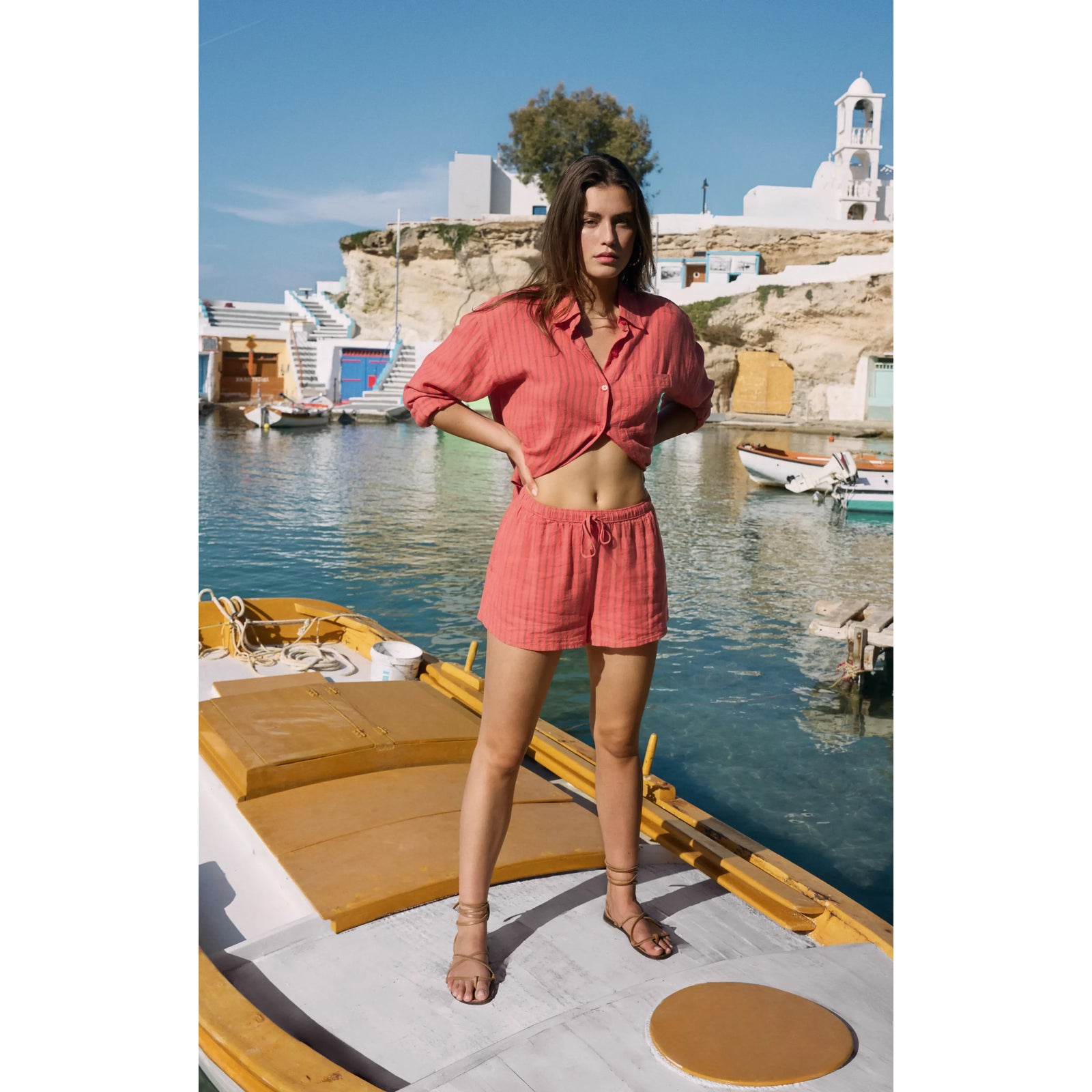 Model wearing Z Supply The Perfect Linen Striped Short in coral by seaside harbor.