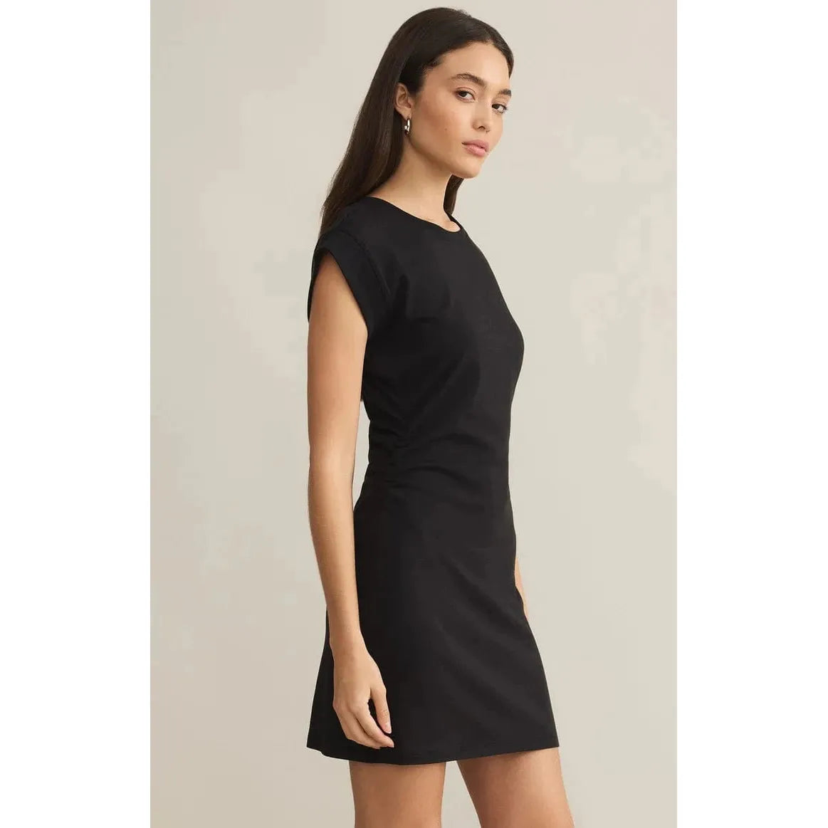 Stylish model showcases the Z Supply Camino Mini Dress, featuring a blouson waist and cap sleeves in classic black.