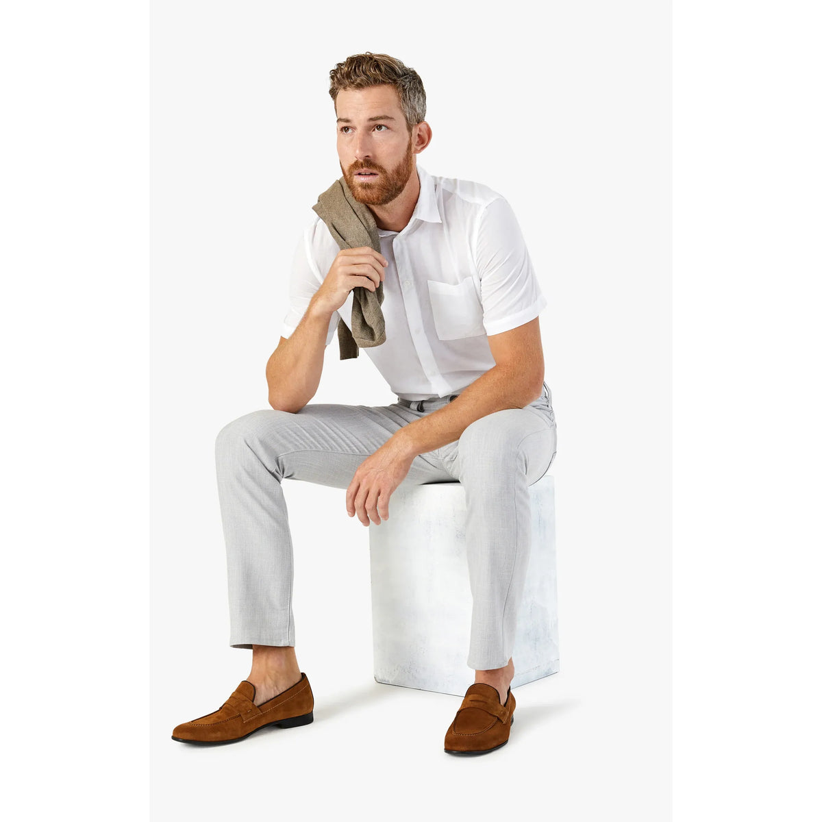 Male model wearing 34 Heritage Courage in Bone Cross Twill pants with white shirt, holding a sweater.