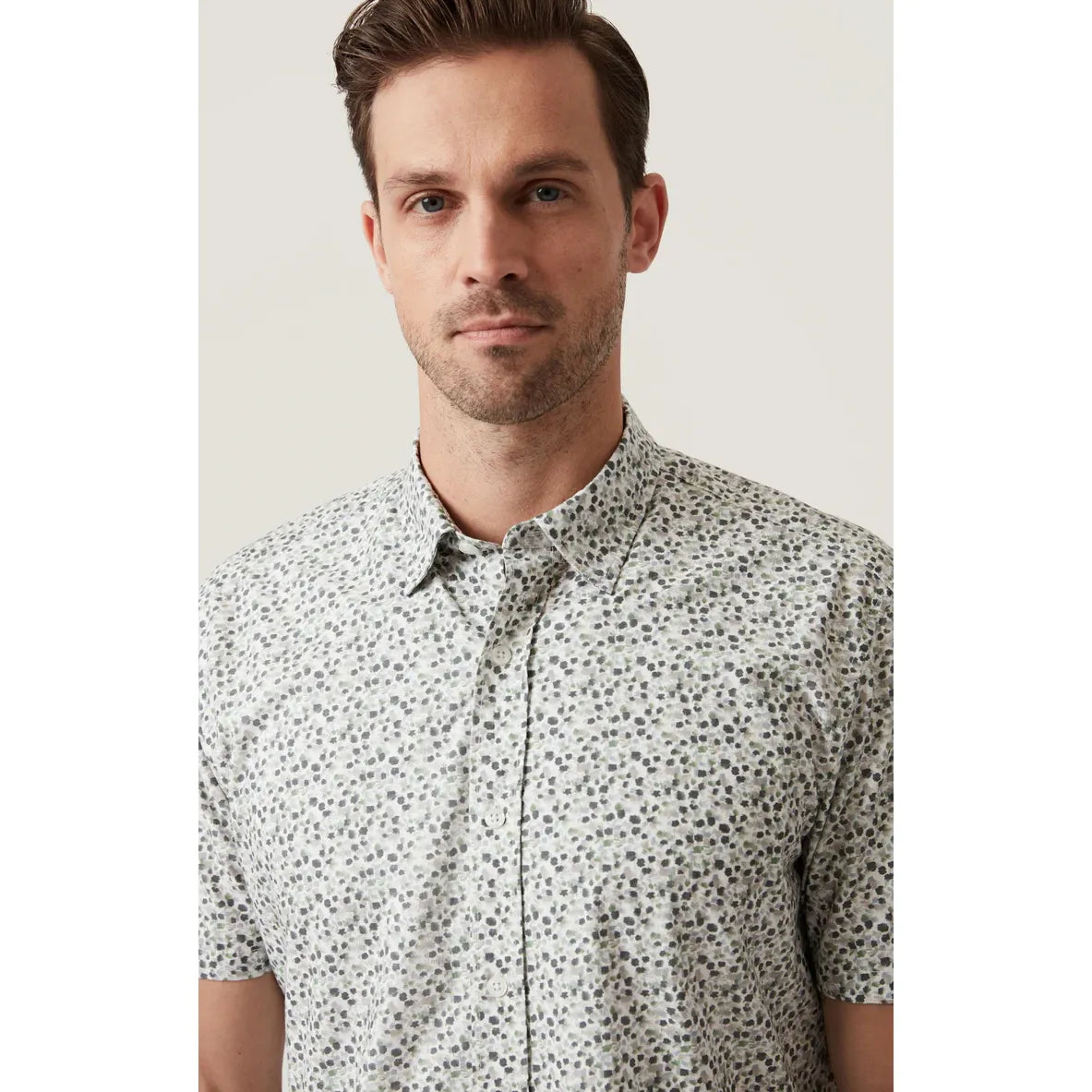 Male model in 34 Heritage Grove Short Sleeve Shirt with cheerful floral print; breathable cotton-Tencel blend.