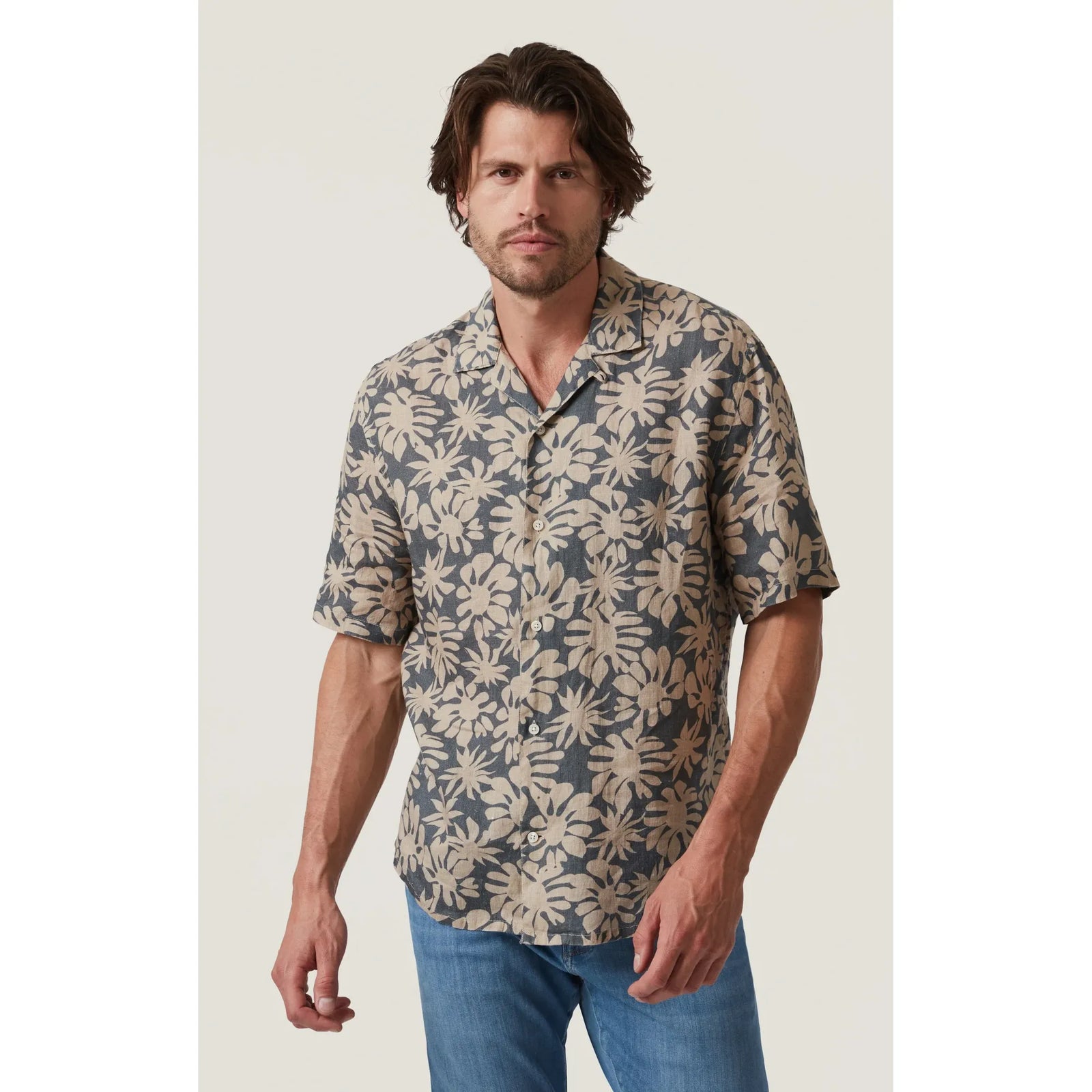 Male model wearing 34 Heritage Bloom Short Sleeve Shirt in blue-gray linen with beige floral print.