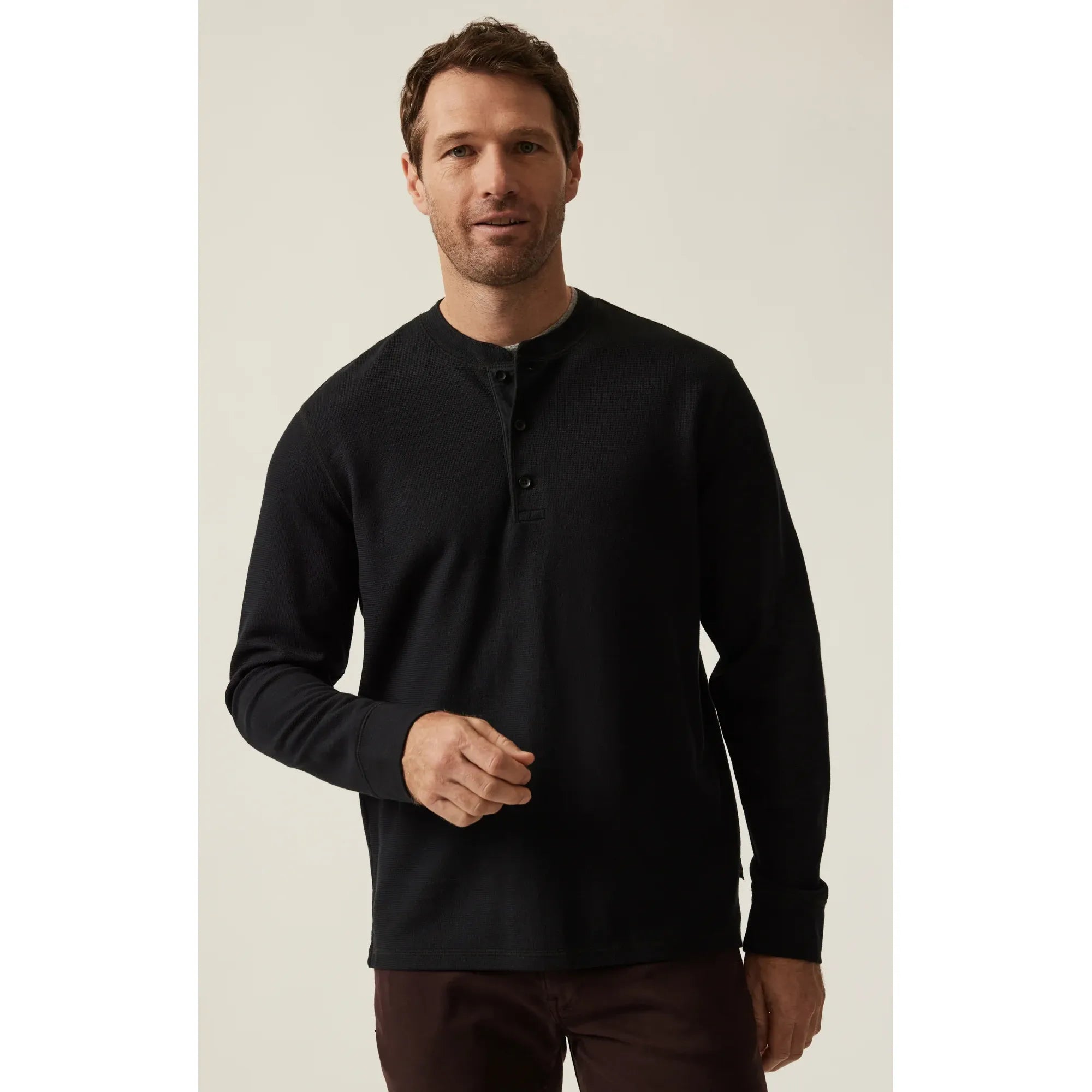 Man wearing black 34 Heritage Long Sleeve Henley with button placket, seated.