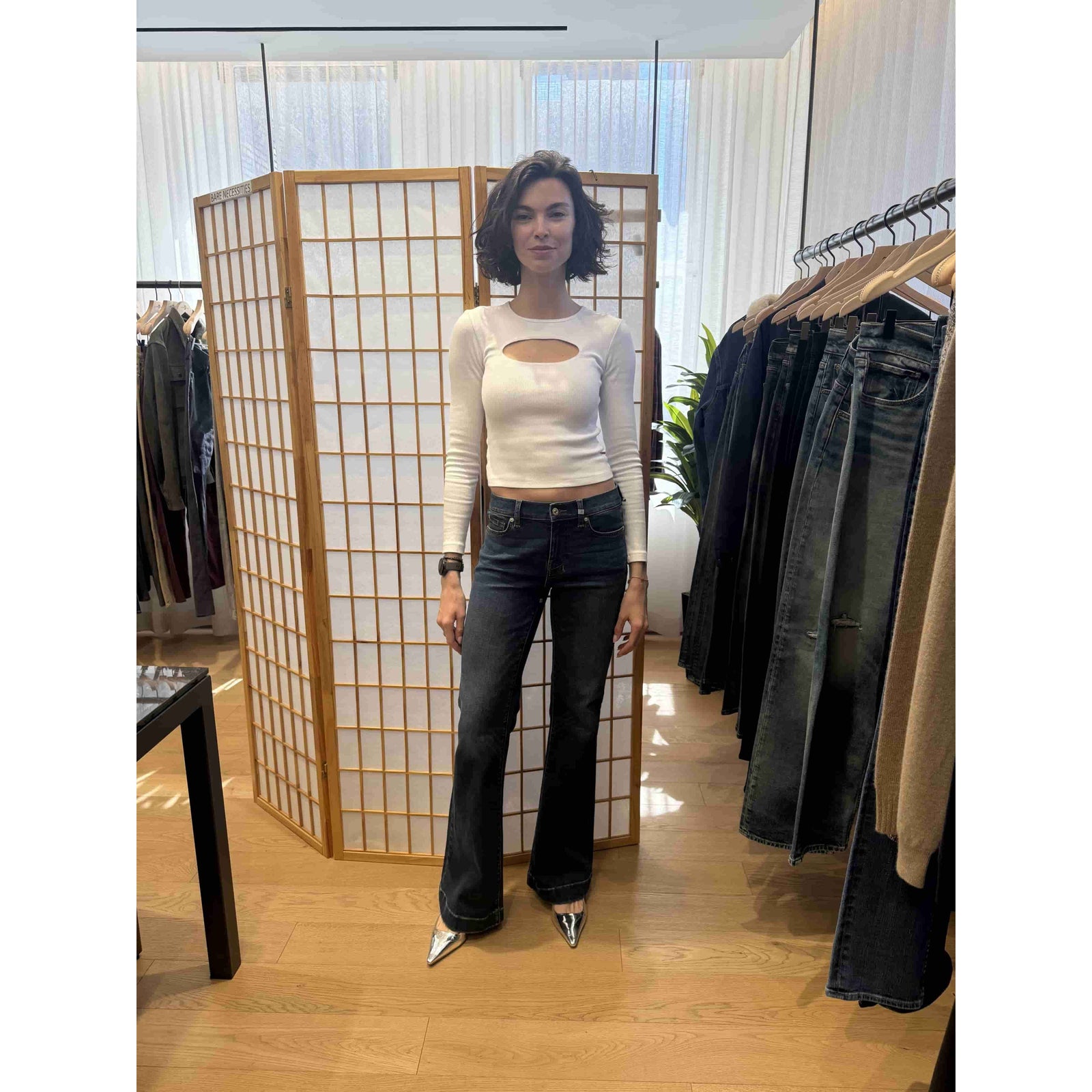 Model wearing 7 For All Mankind Dojo in Koko dark flare jeans with white cutout top in a boutique.