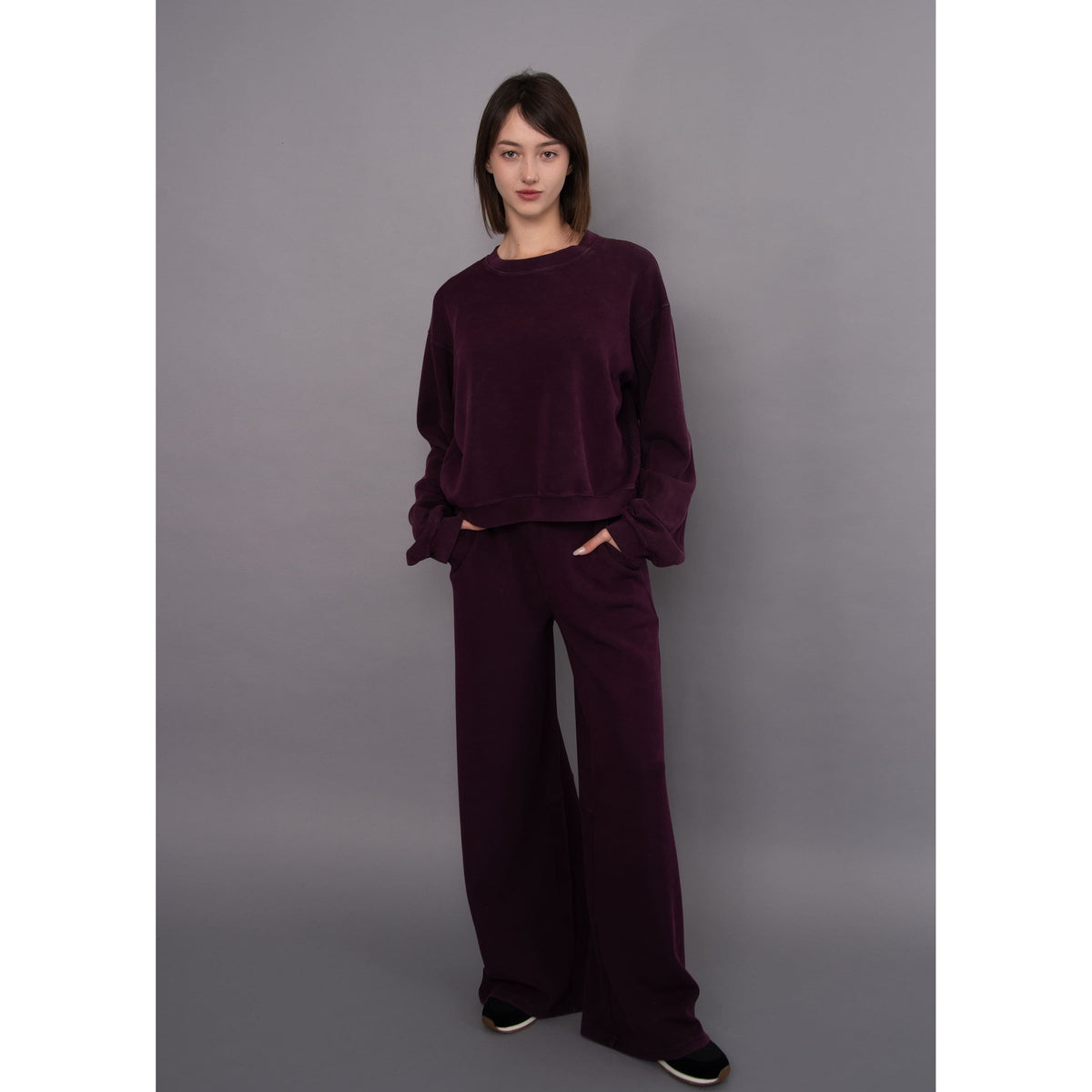 Model wears a deep purple Beatrice soft knit pullover with matching wide-leg pants for a cozy, relaxed everyday look.