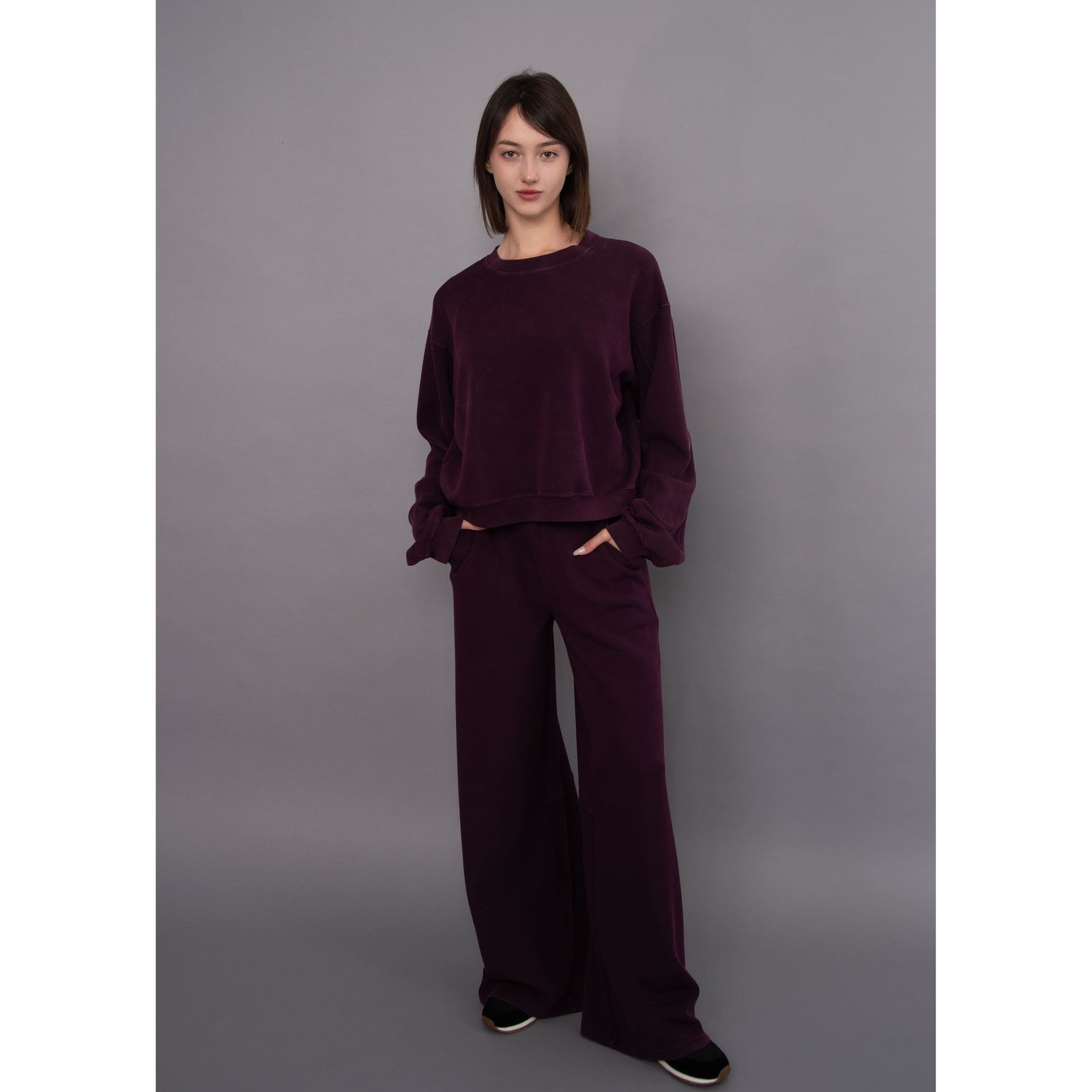 Model wears a deep purple Beatrice soft knit pullover with matching wide-leg pants for a cozy, relaxed everyday look.