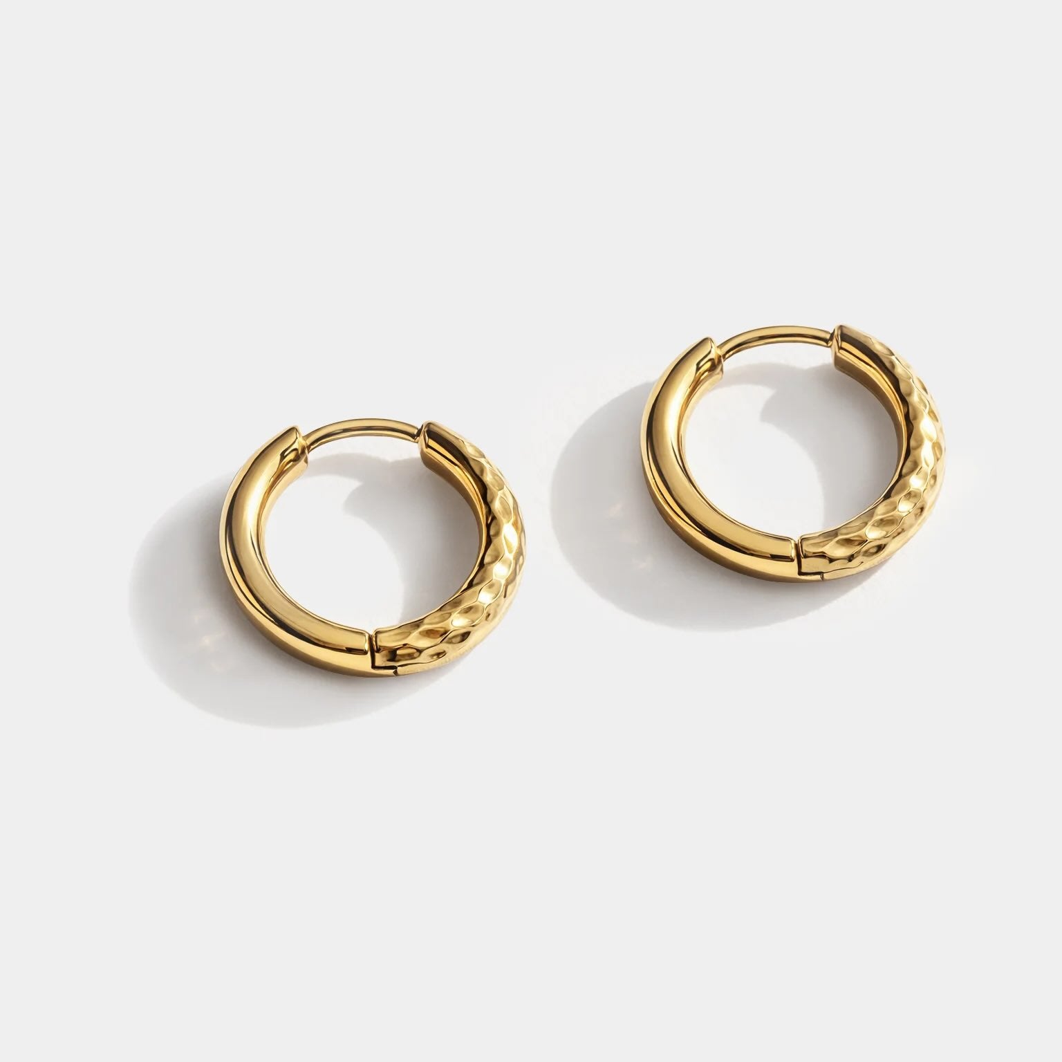 Gold hammered hoop huggie earrings with textured finish in stainless steel.
