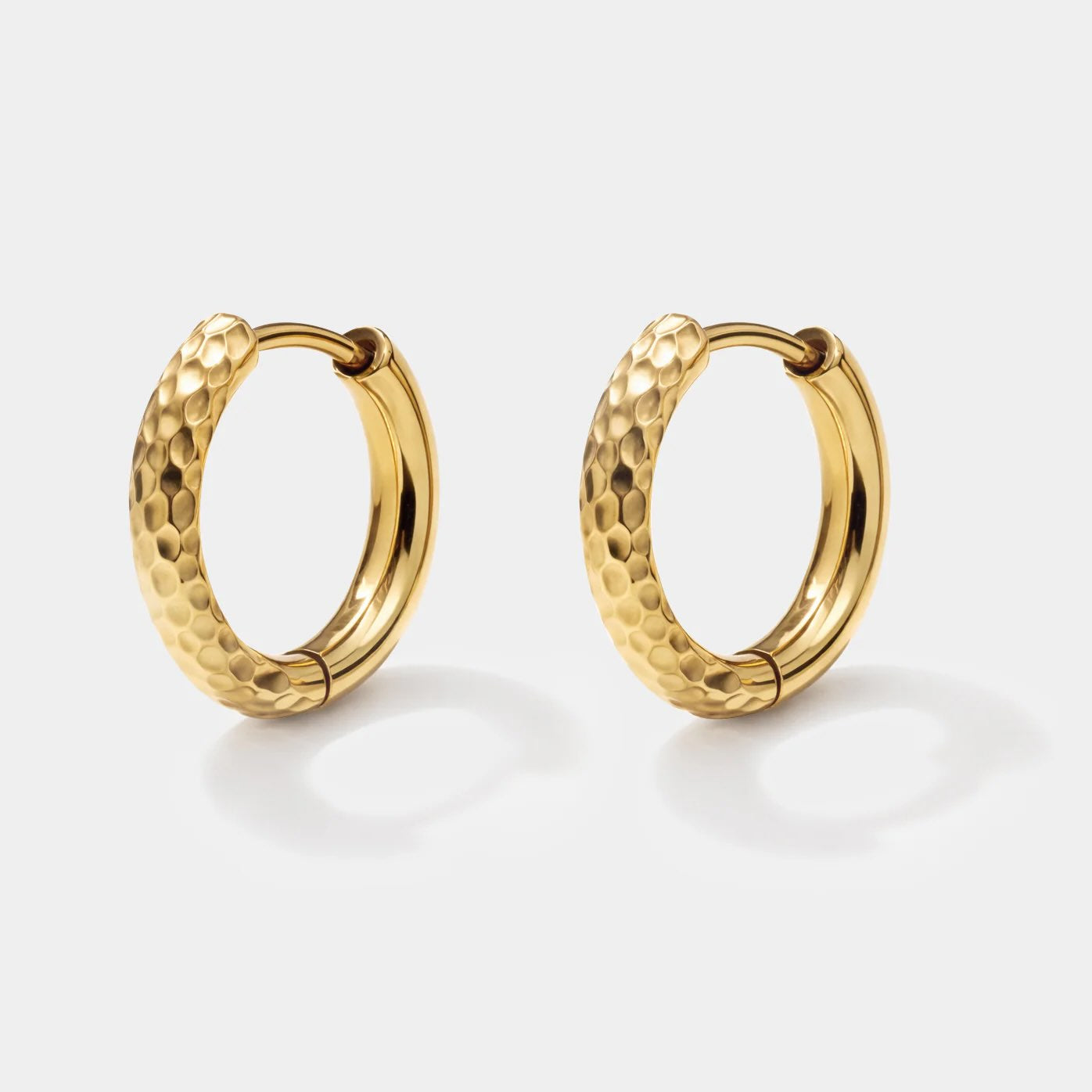 Gold hammered hoop huggie earrings with textured finish in stainless steel.