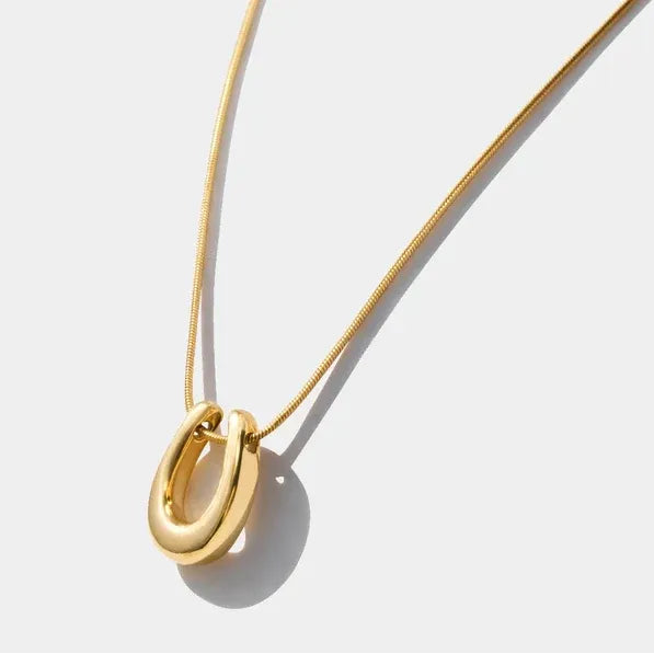Gold-tone horseshoe charm necklace on a fine chain. Stainless steel, hypoallergenic, and water-resistant good luck pendant for daily wear.