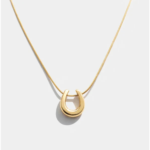 Gold-tone stainless steel horseshoe charm necklace on a fine chain. Dainty good luck pendant, hypoallergenic and water-resistant.
