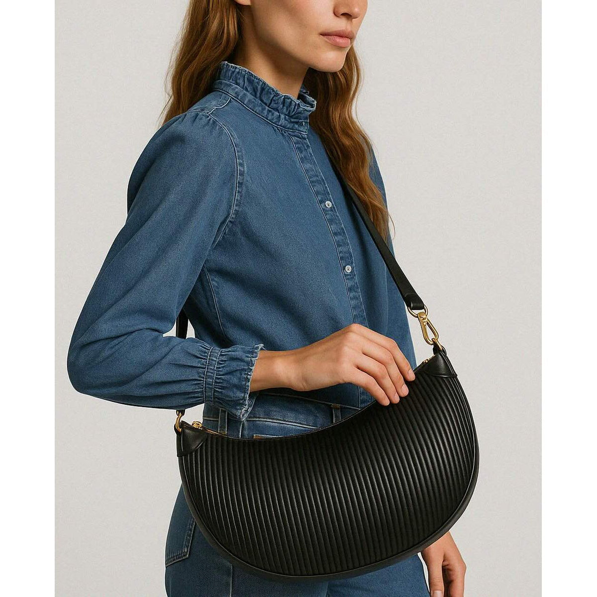 Black Crescent Moon Wavy PU Crossbody Handbag with gold hardware, carried by a model in blue denim top.